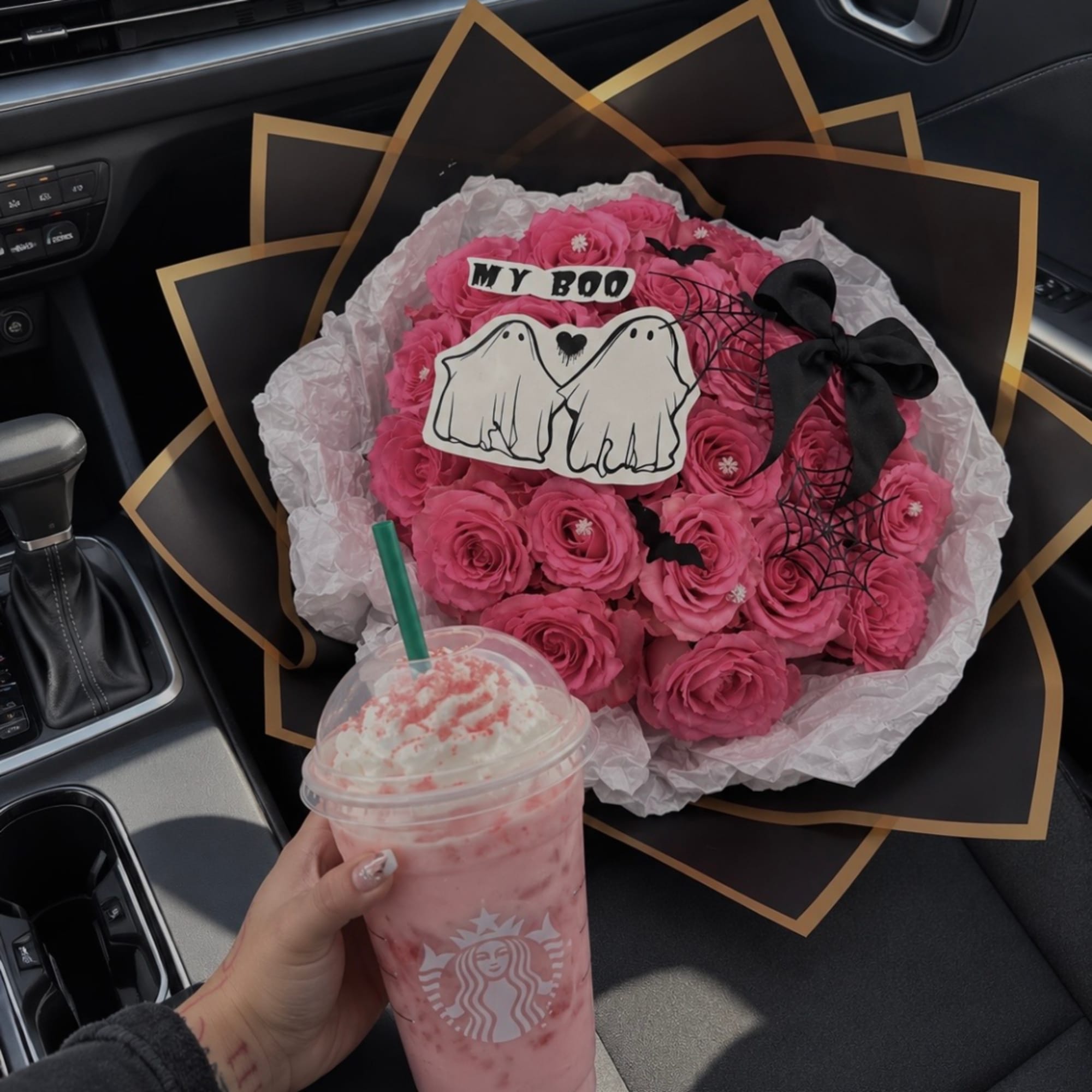 Pink rose bouquet with Halloween ghost decorations and a black ribbon in a car