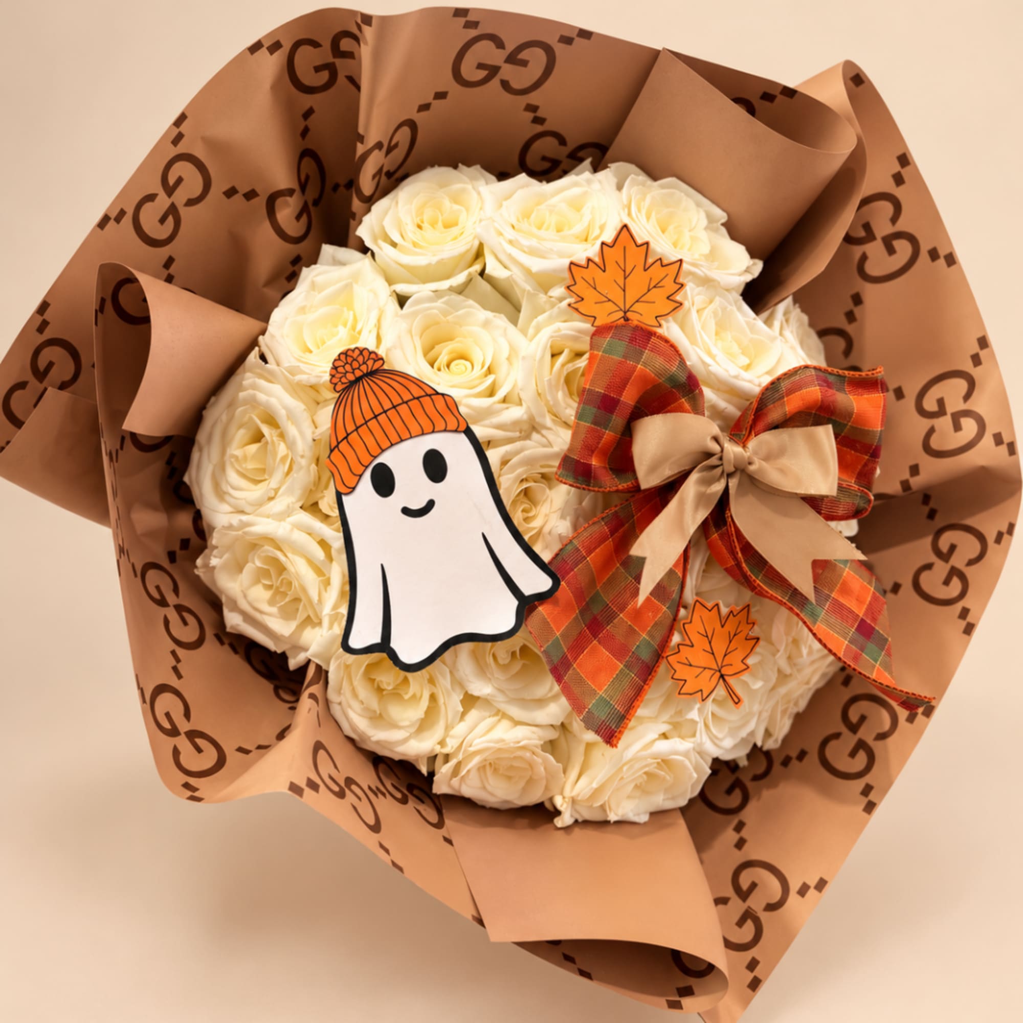Bouquet of cream roses wrapped in brown paper with a plaid bow and Halloween decorations