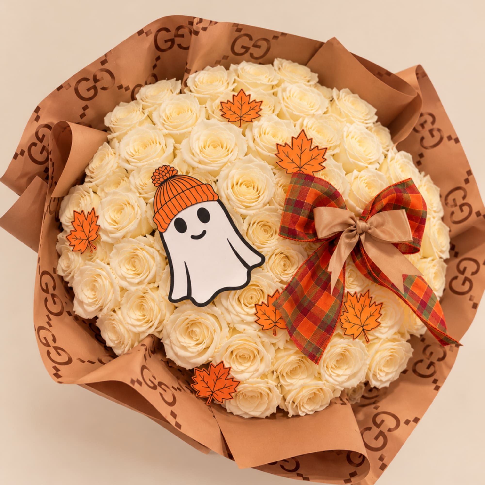 Bouquet of cream roses wrapped in brown paper with a plaid bow and Halloween decorations