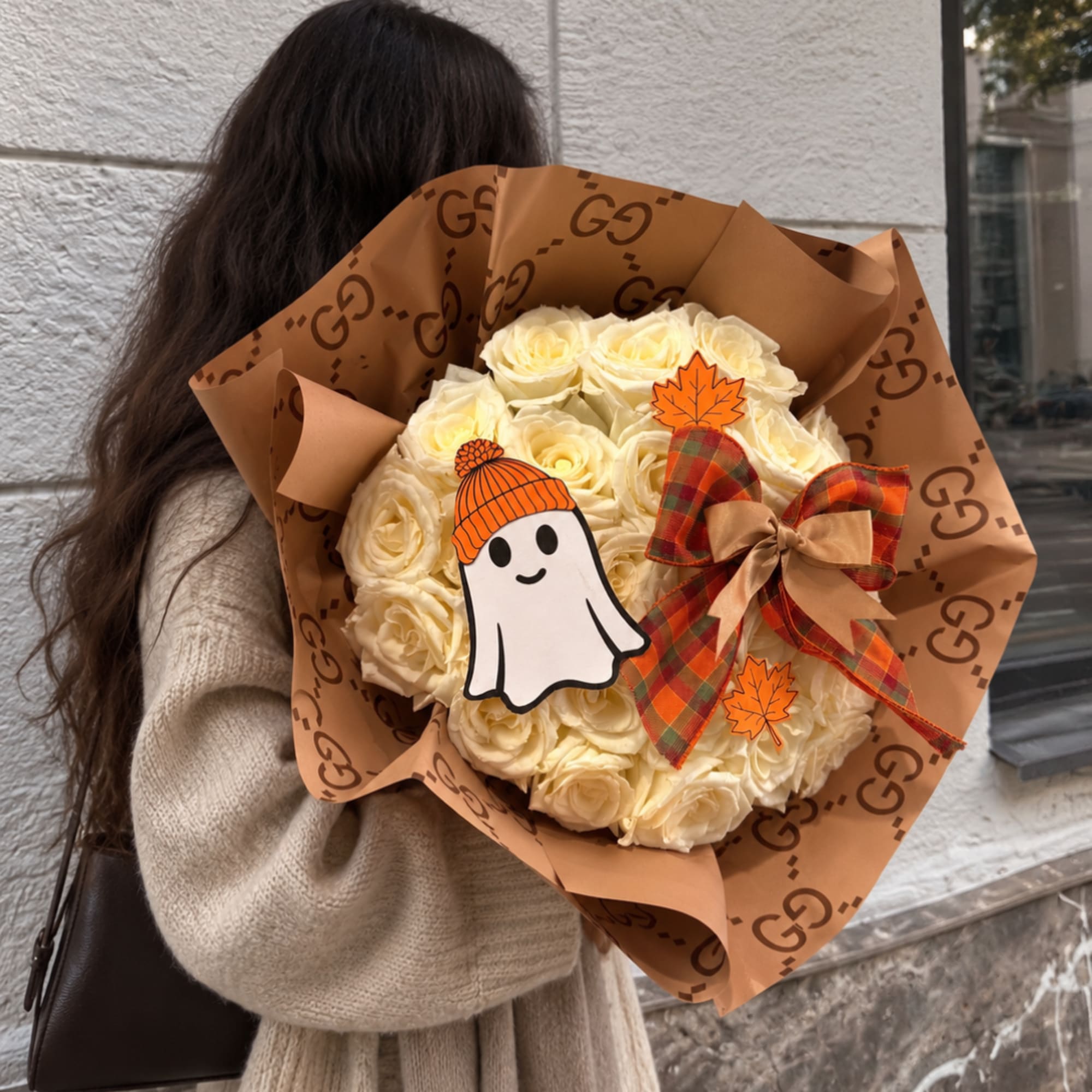 Cream rose bouquet wrapped in brown paper with a Halloween ghost decoration