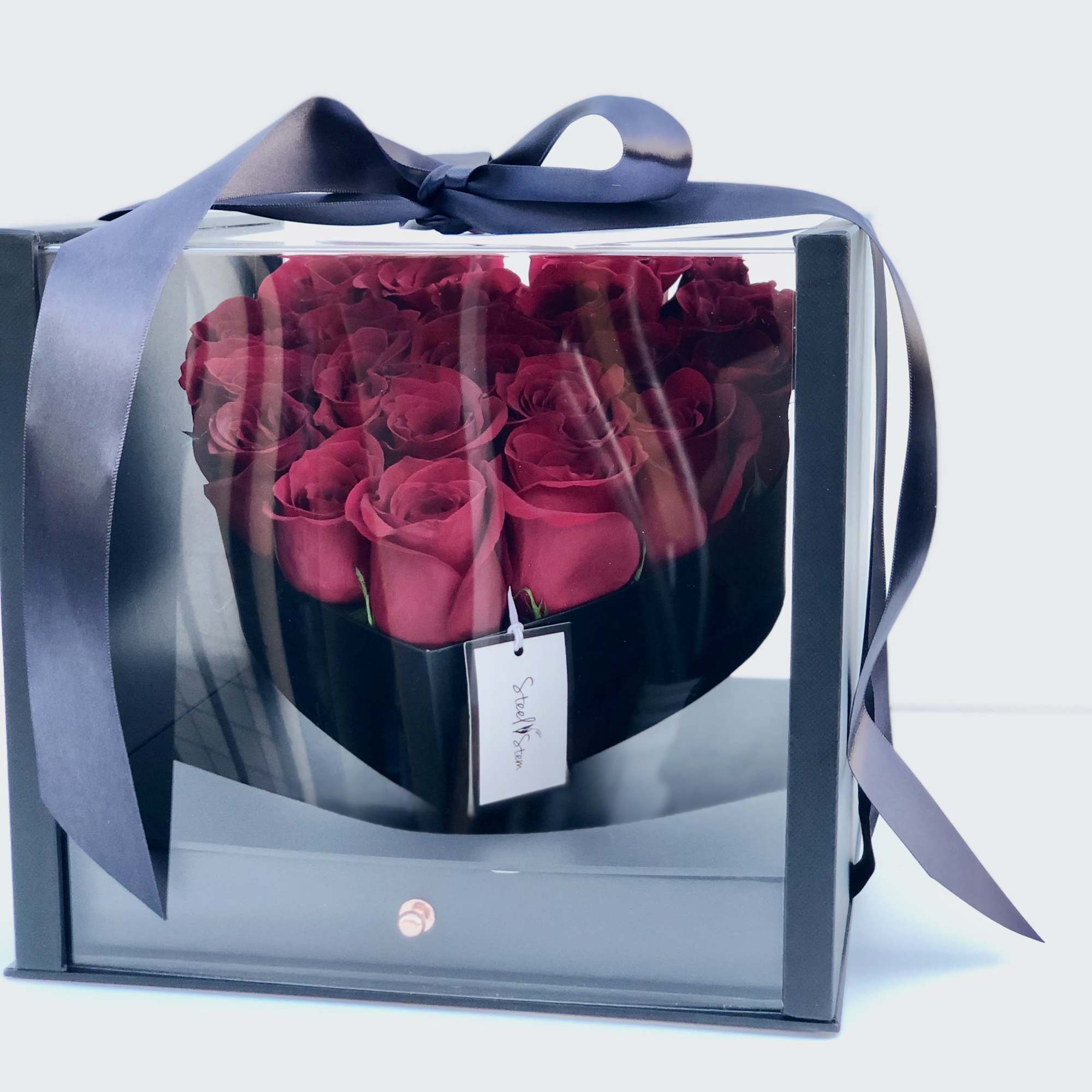 Boxed arrangement of deep pink roses with a navy ribbon