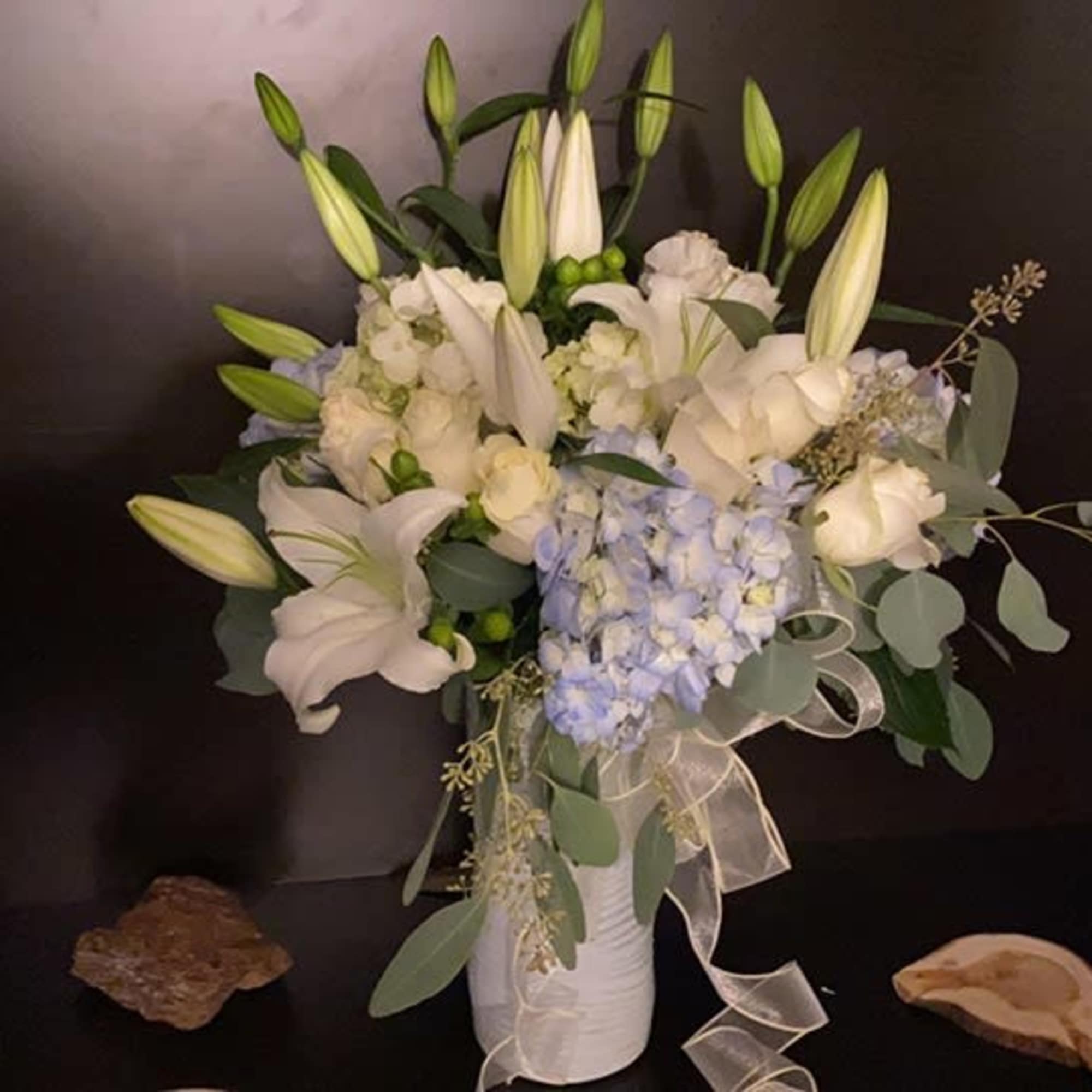 White lilies and pale blue hydrangeas in a white vase with ribbon, photo 4 of 9