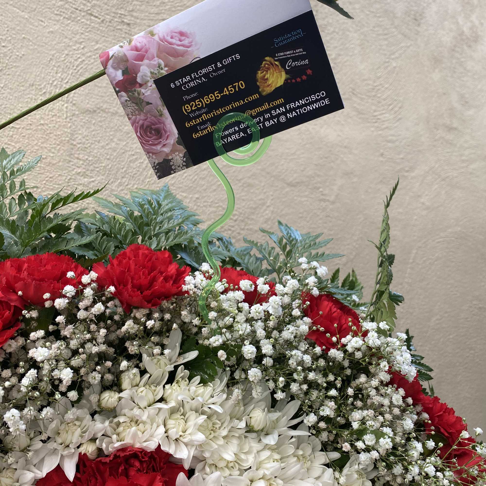 Red and white floral arrangement with a yellow rose and business card