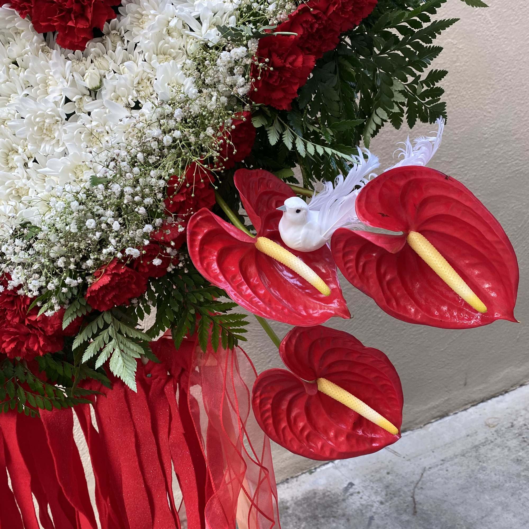 Red and white floral arrangement with anthuriums and ribbon streamers