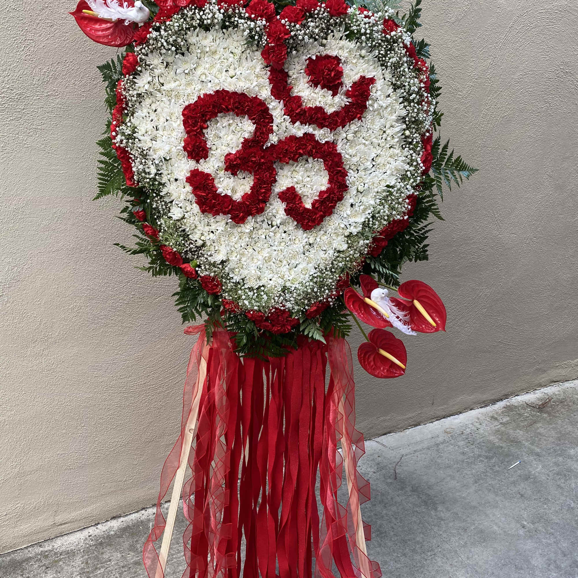 Heart-shaped red and white floral standing spray with ribbons