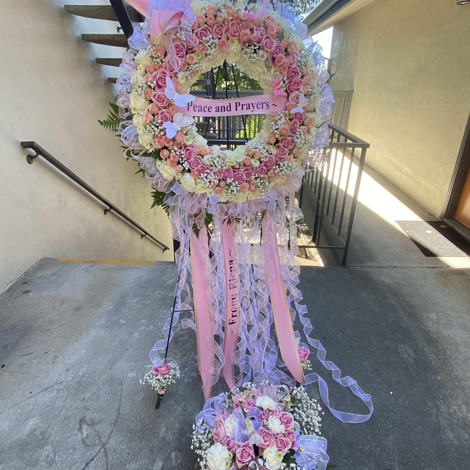 Large pink and white floral standing wreath with ribbons and a "Peace and Prayers" sign, photo 11 of 21