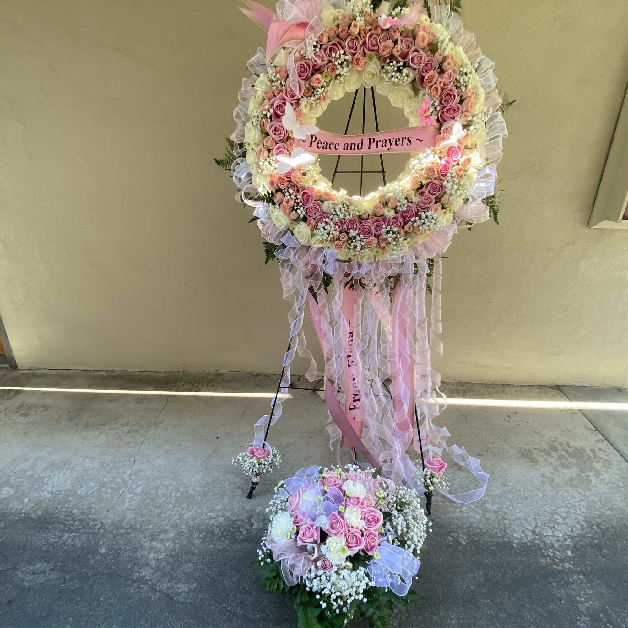 Large pink and white floral standing wreath with ribbons and a "Peace and Prayers" sign, photo 19 of 21