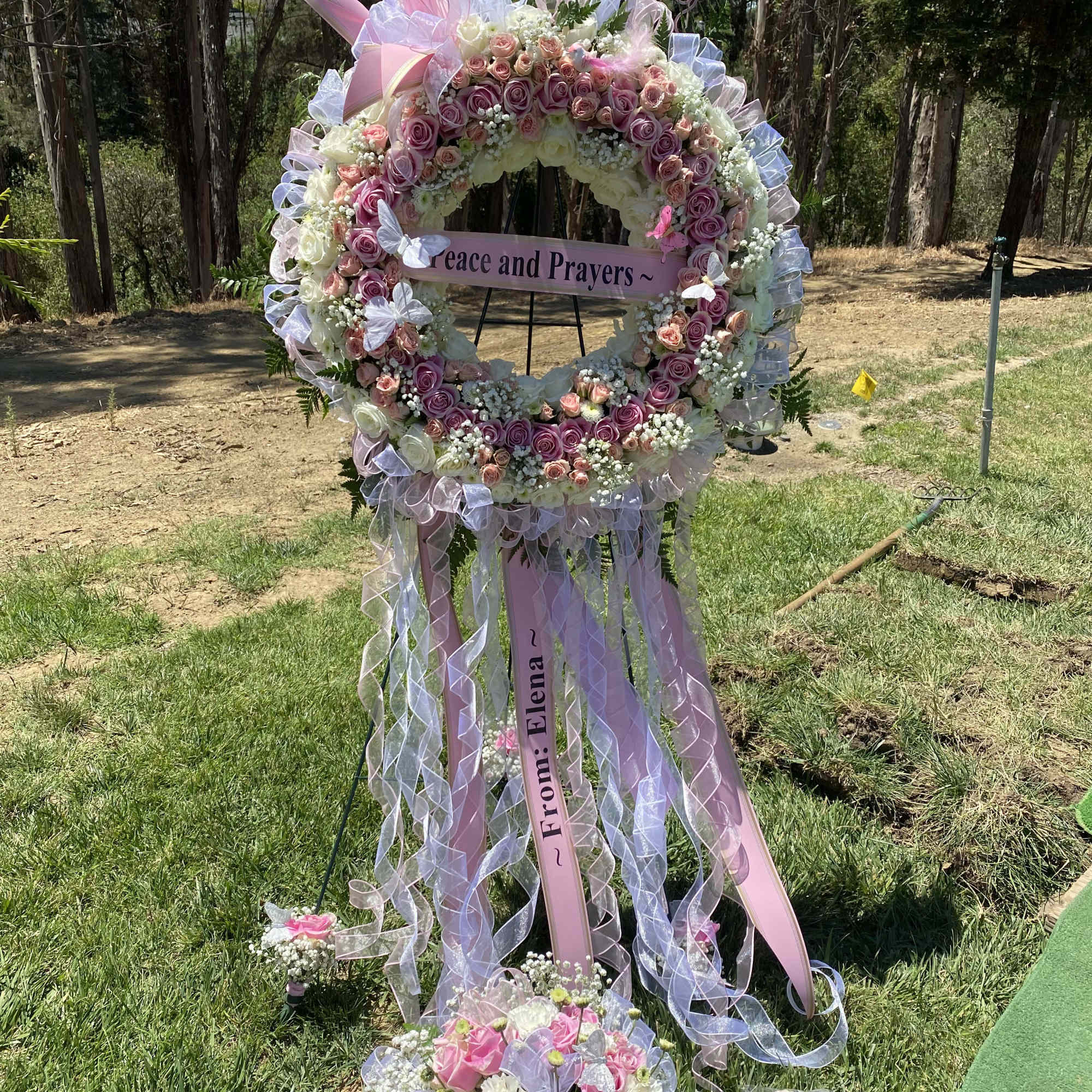 Large floral wreath with pink and white roses and ribbons on a stand