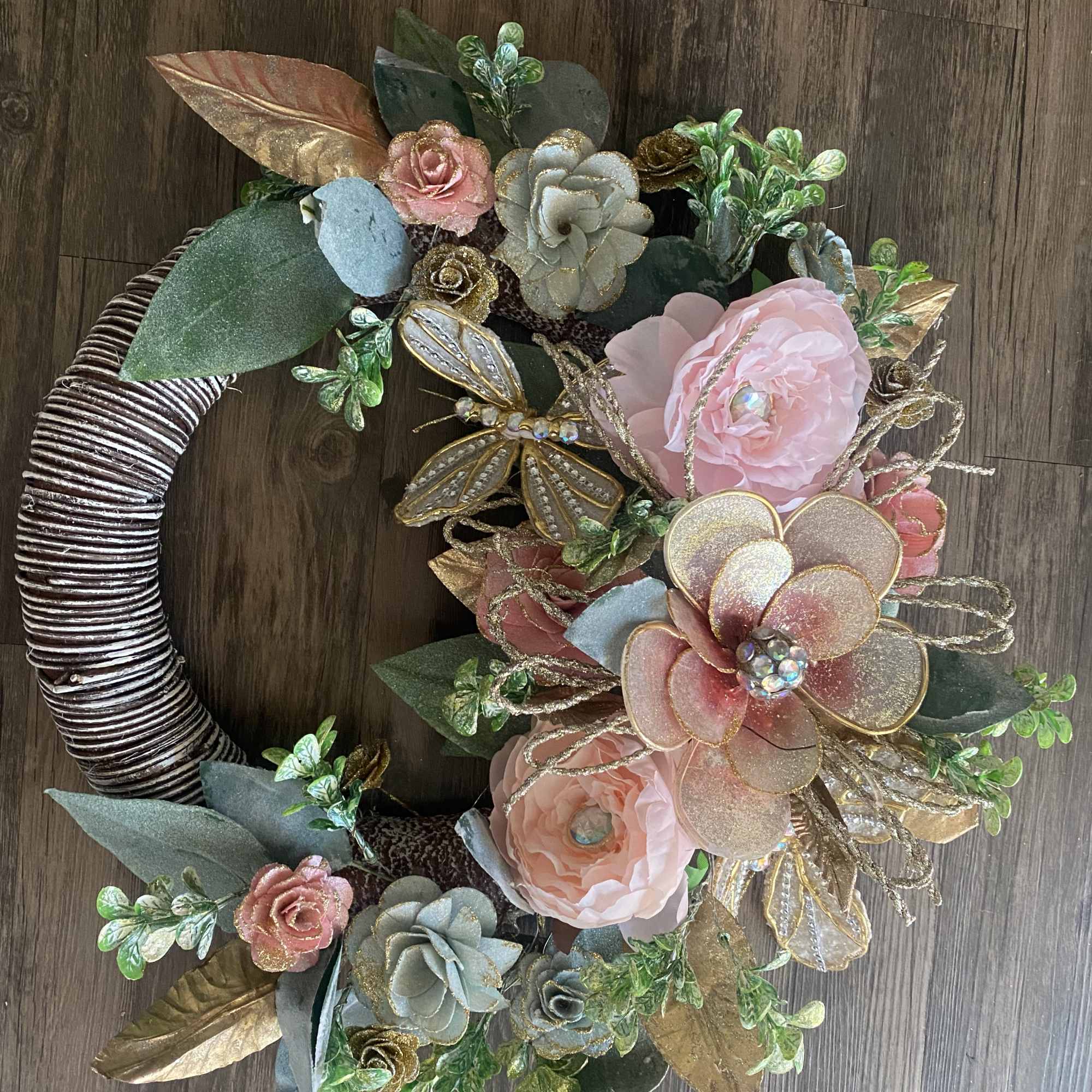 Floral wreath with pink and gold flowers on a wrapped circular base
