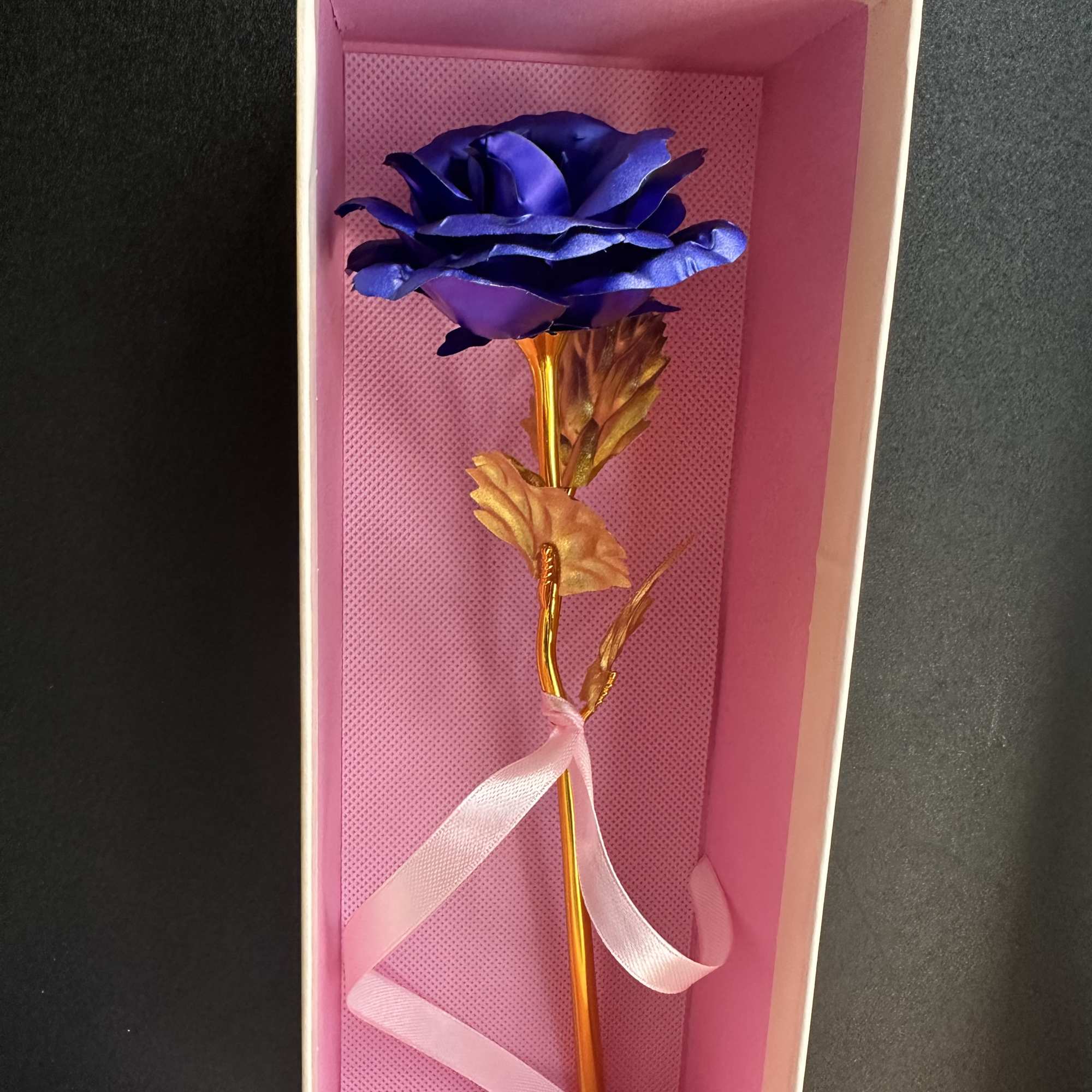 Single blue rose in a pink gift box with a ribbon