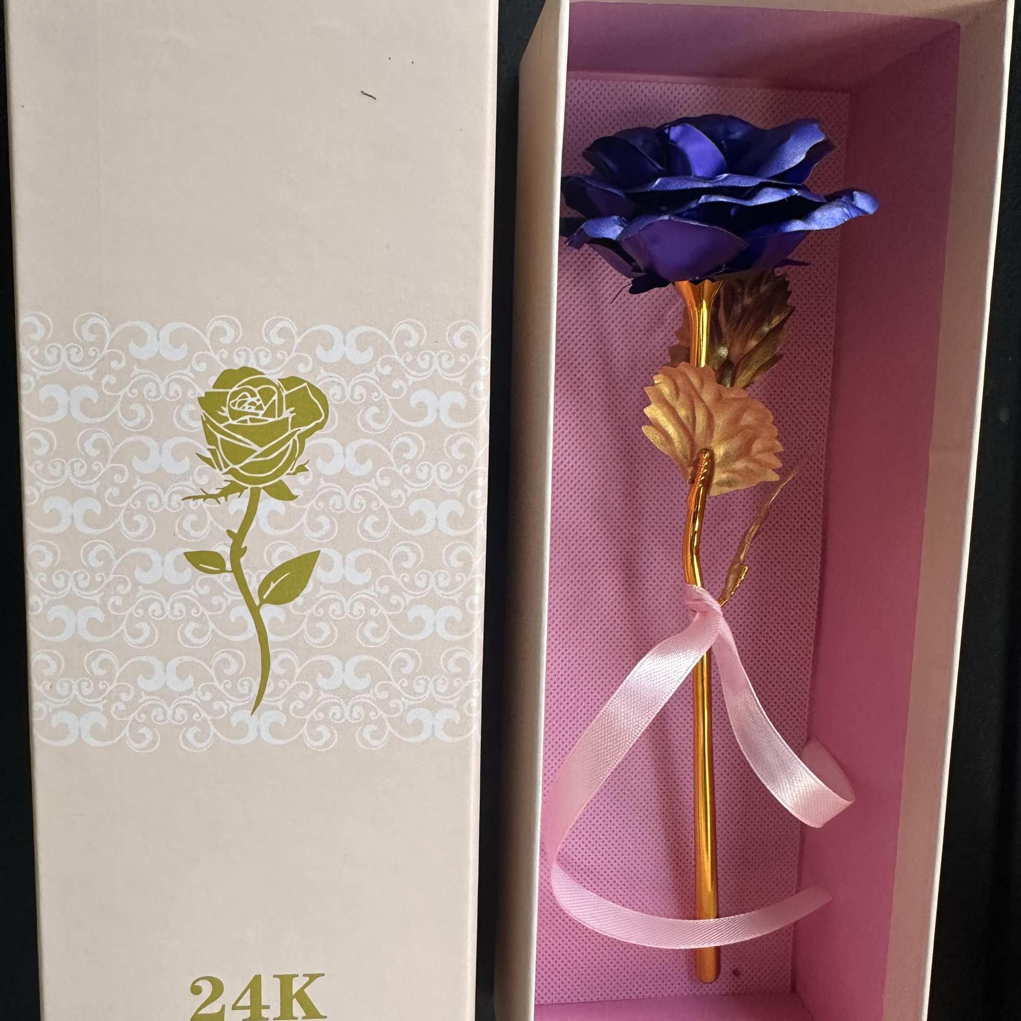 Gift box with a gold rose and purple flower inside