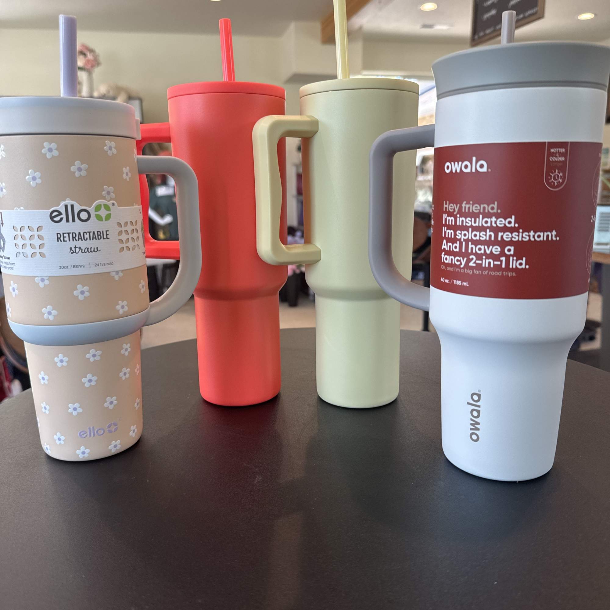 Four insulated tumblers with straws on a table