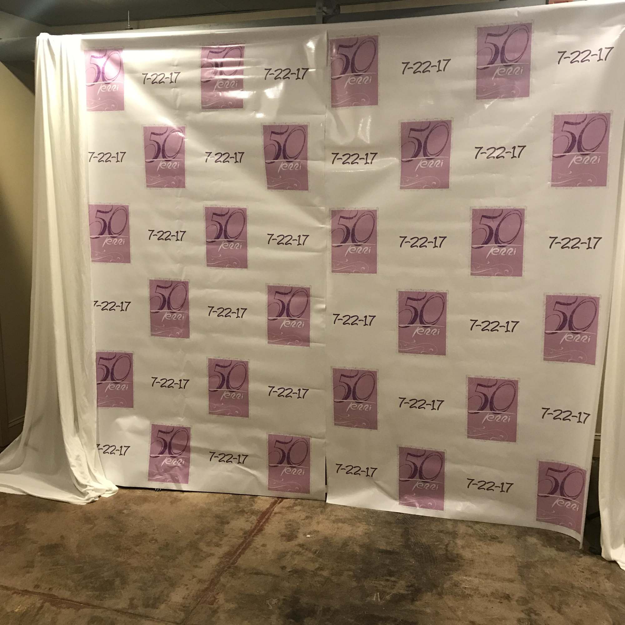 White event backdrop with repeated pink "50" and date text