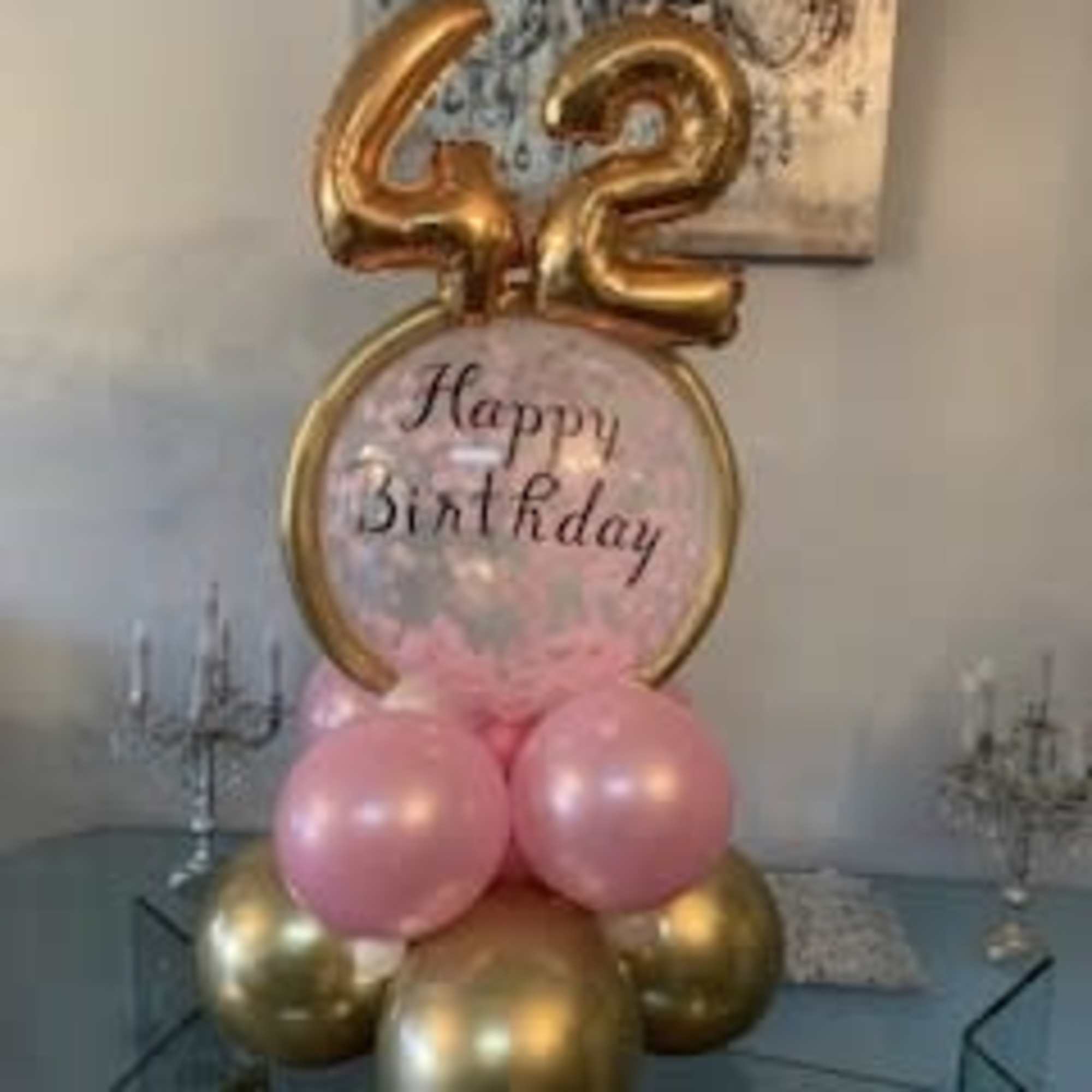 Pink and gold birthday balloon display with a "42" topper