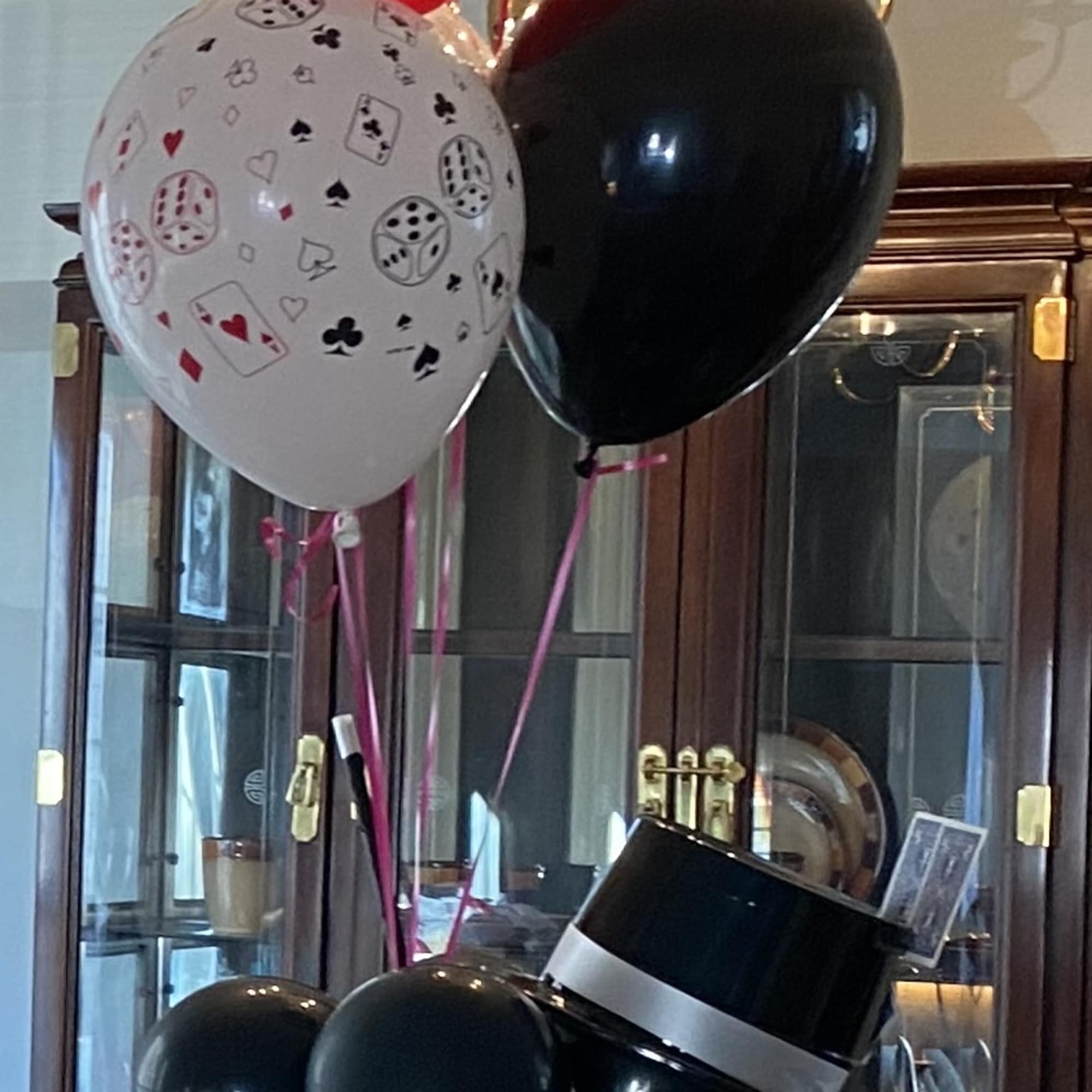 Cluster of red, black, and white balloons with playing-card prints and a top hat balloon