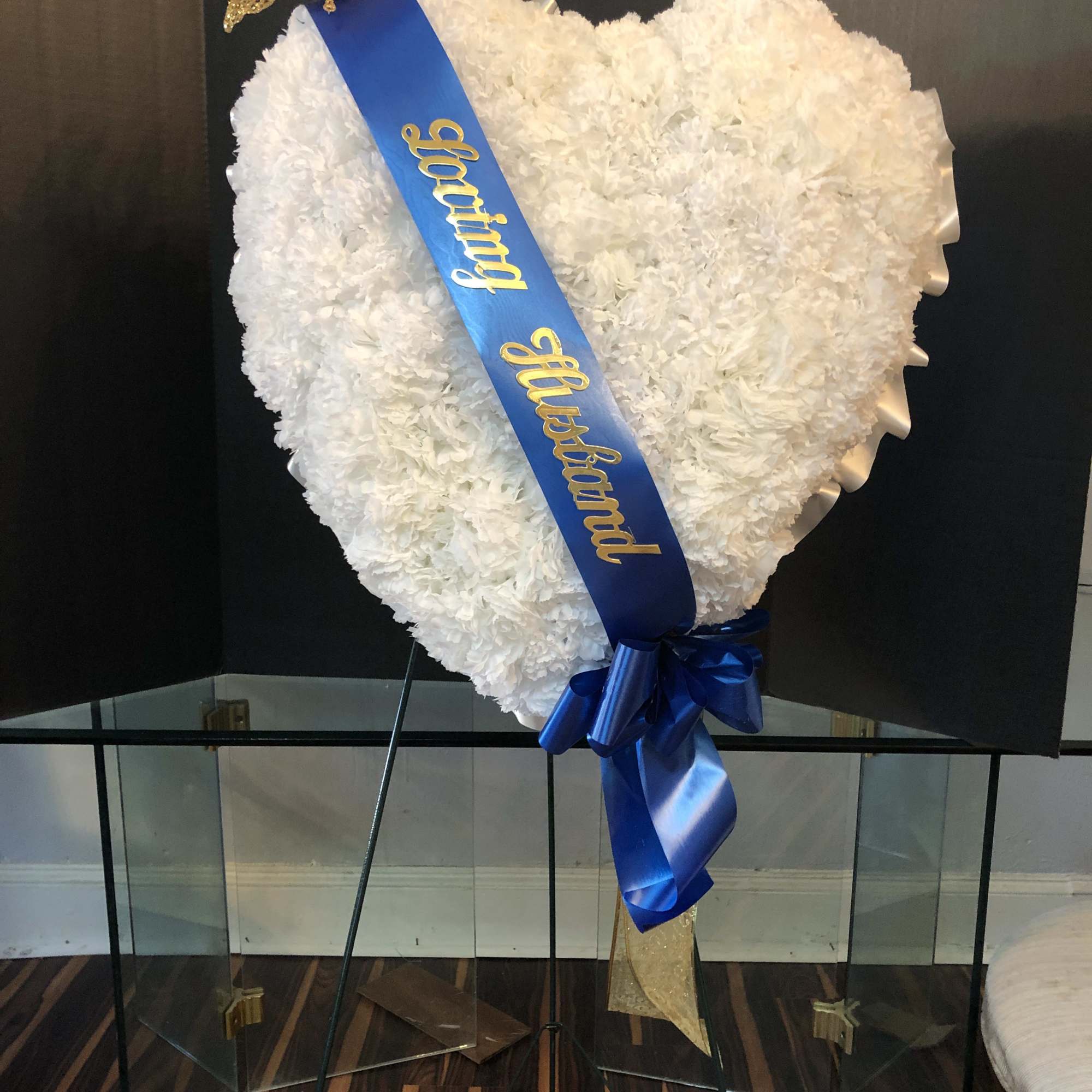 Heart-shaped white floral standing spray with a blue ribbon