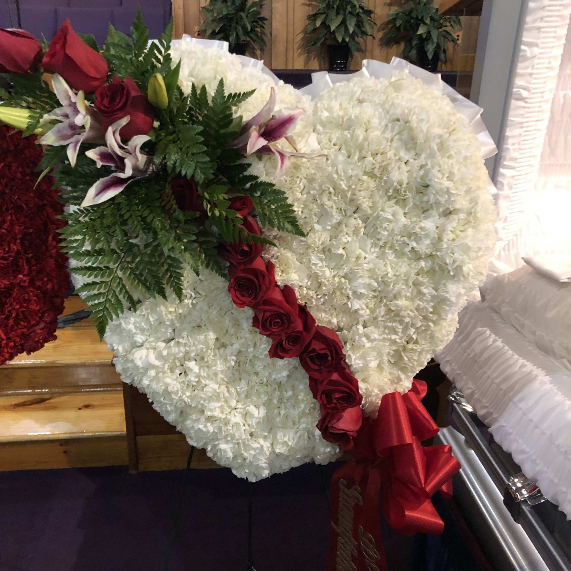 Heart-shaped white floral spray with red roses and lilies