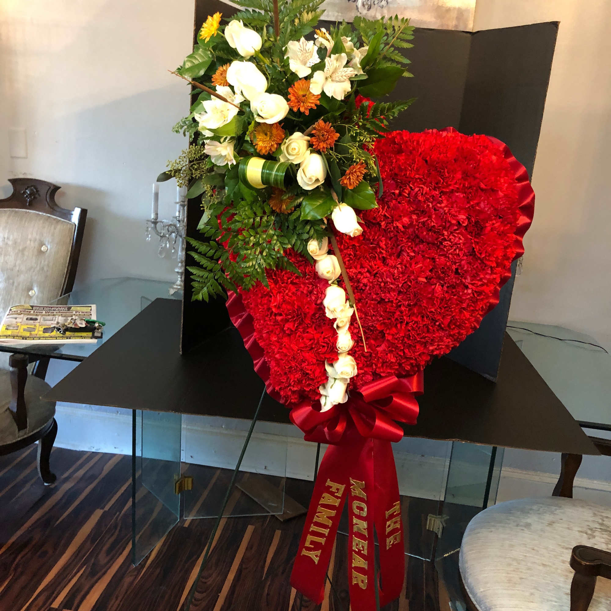 Heart-shaped red floral tribute with white roses and a red ribbon