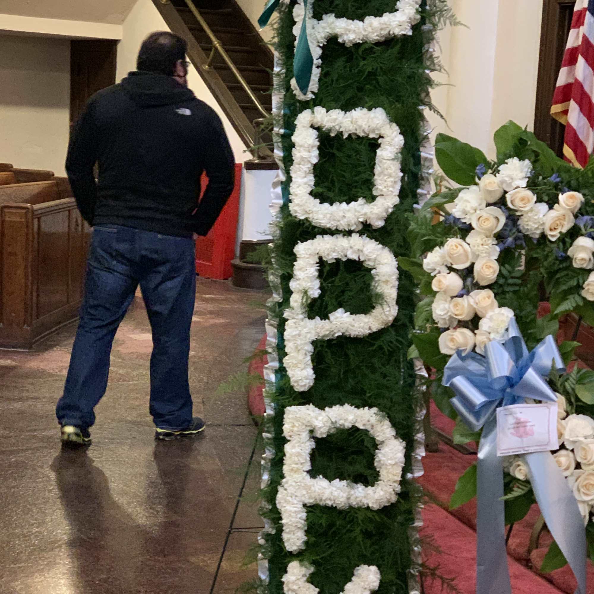 Tall floral standing tribute with white flowers spelling "PEACE"