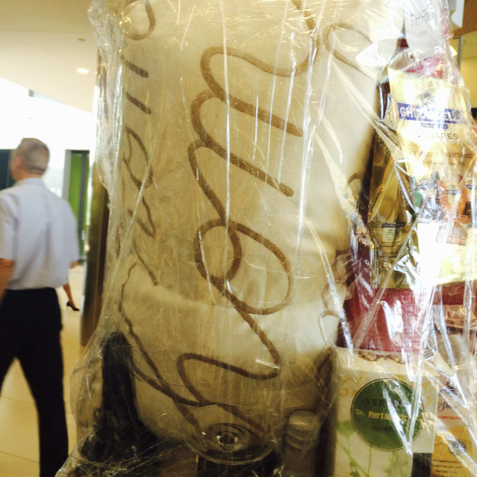Wrapped gift basket with a tall decorative container and packaged items