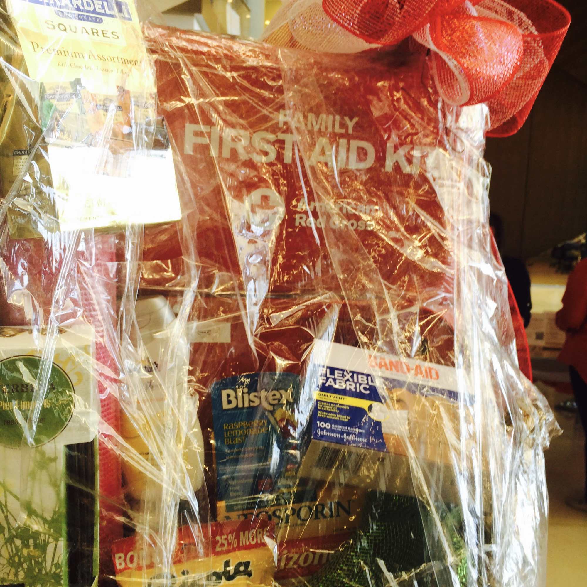 Gift basket with assorted packaged snacks and a red ribbon bow