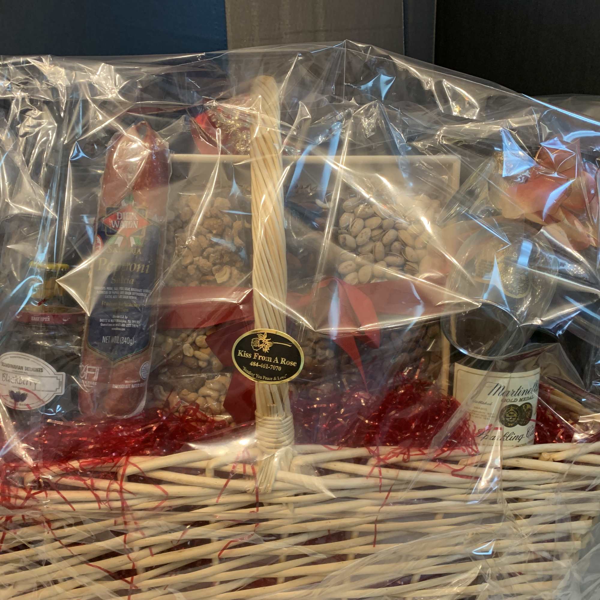 Gift basket with wine, snacks, and packaged treats wrapped in clear plastic