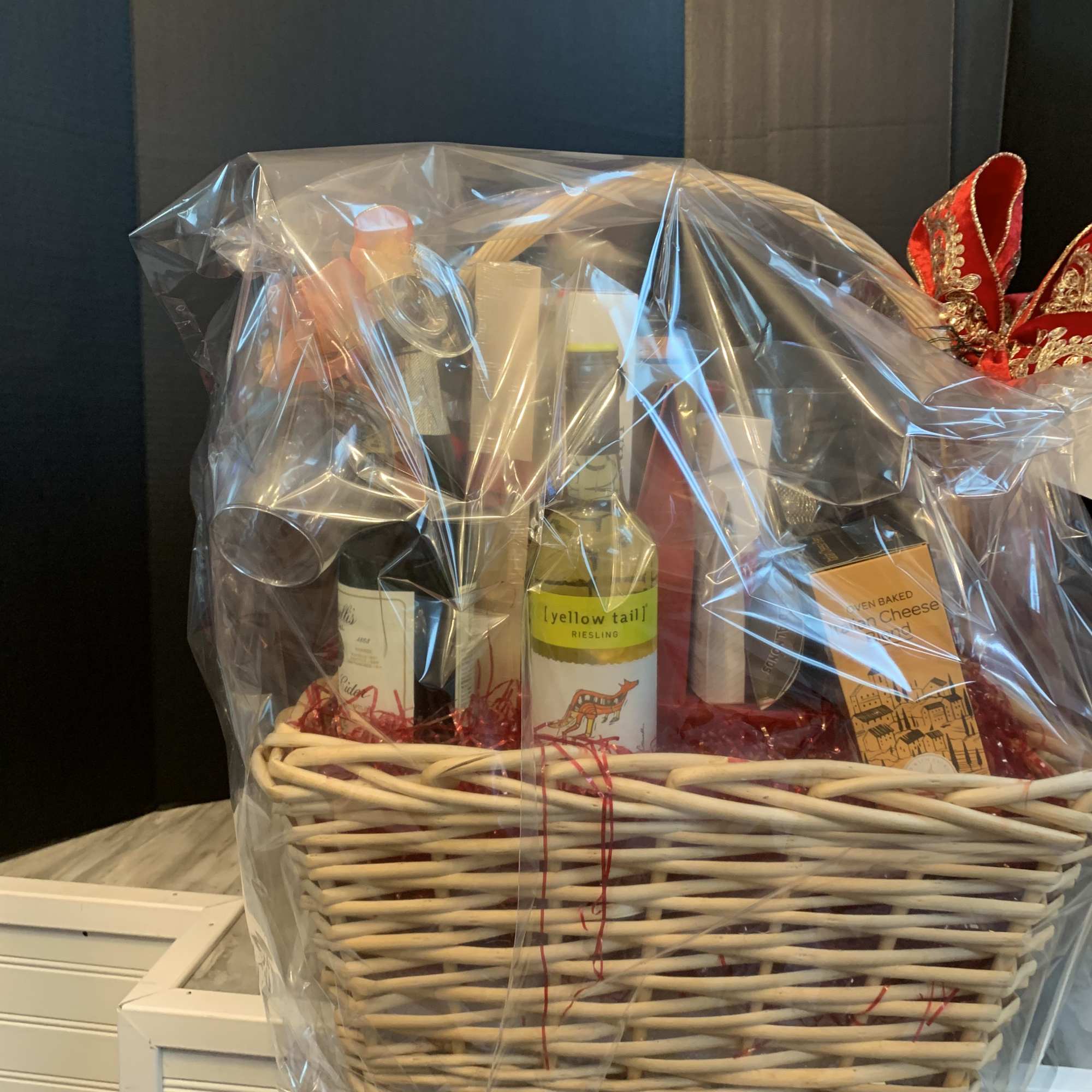 Gift basket with wine bottles and packaged snacks in a wicker basket