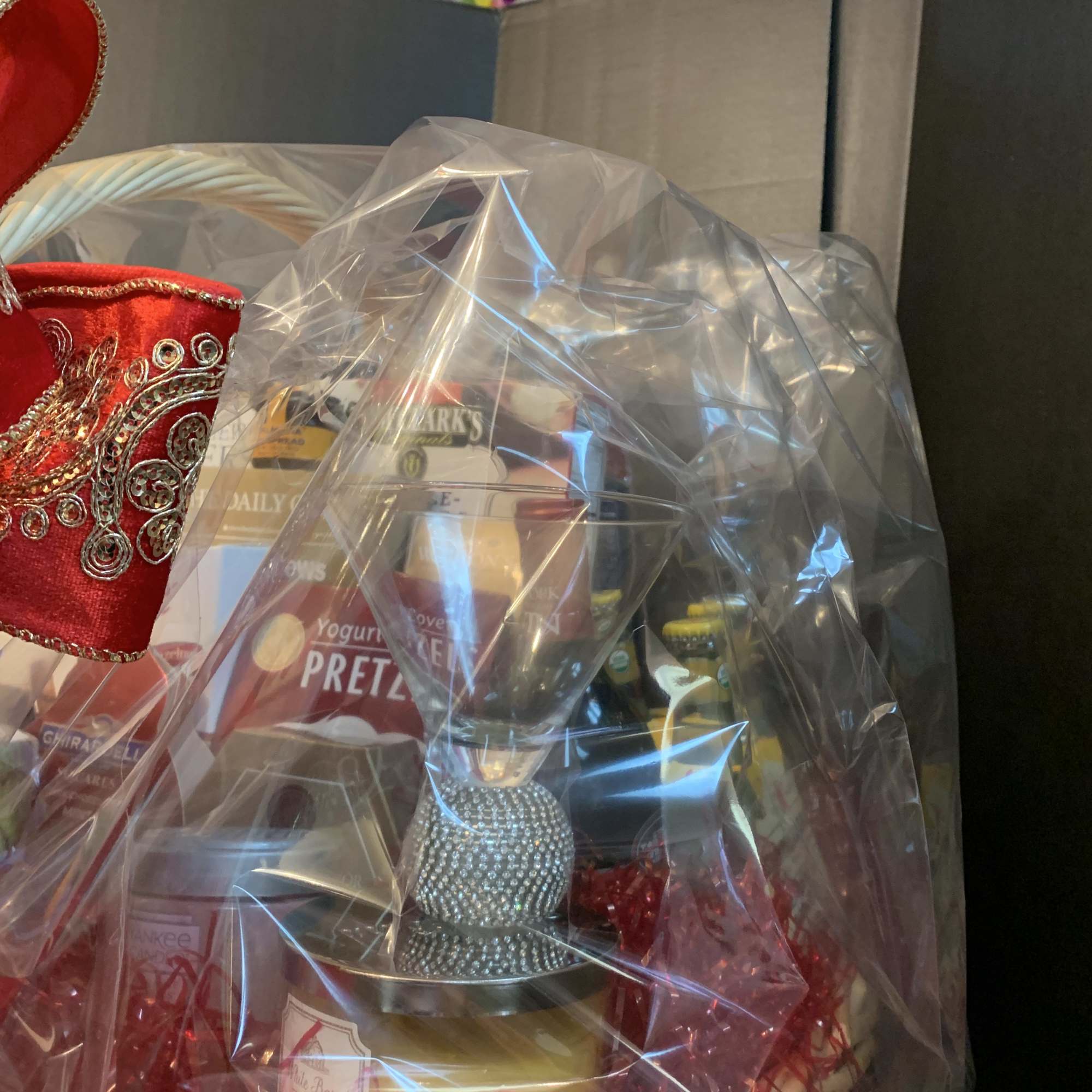 Gift basket with snacks and a wine glass wrapped in clear cellophane