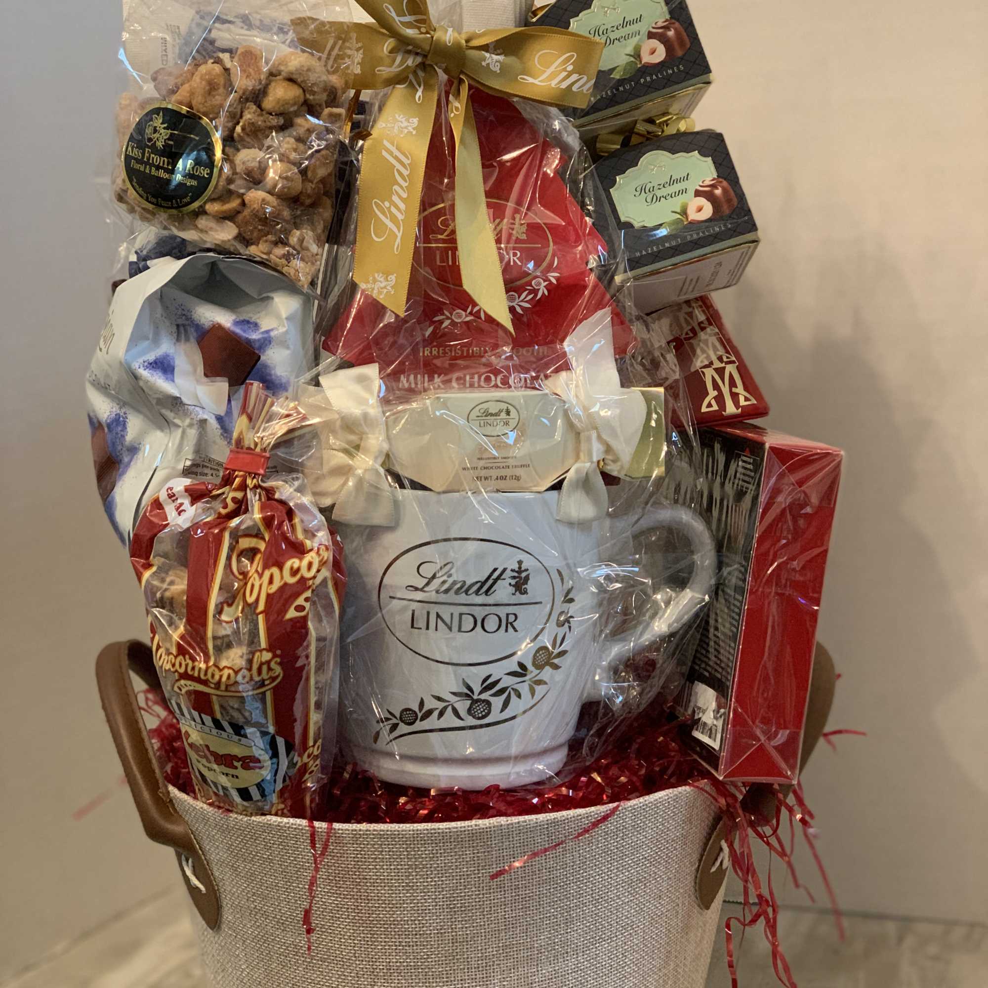 Gift basket with chocolates, snacks, and a mug in a fabric tote