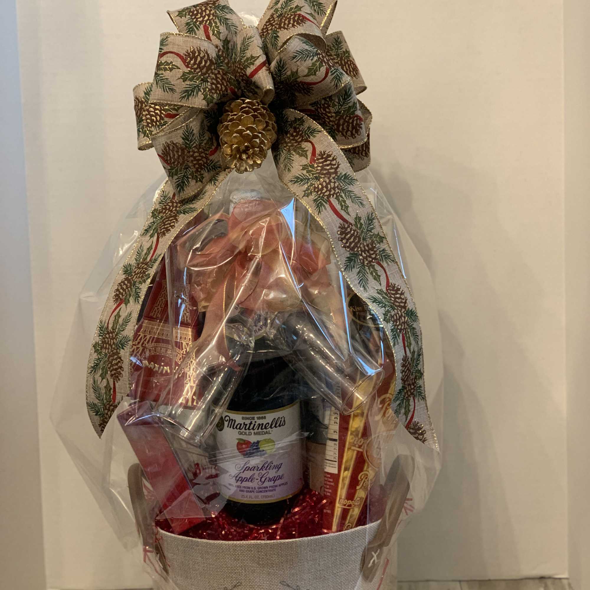 Gift basket with sparkling cider, chocolates, and a large holiday bow