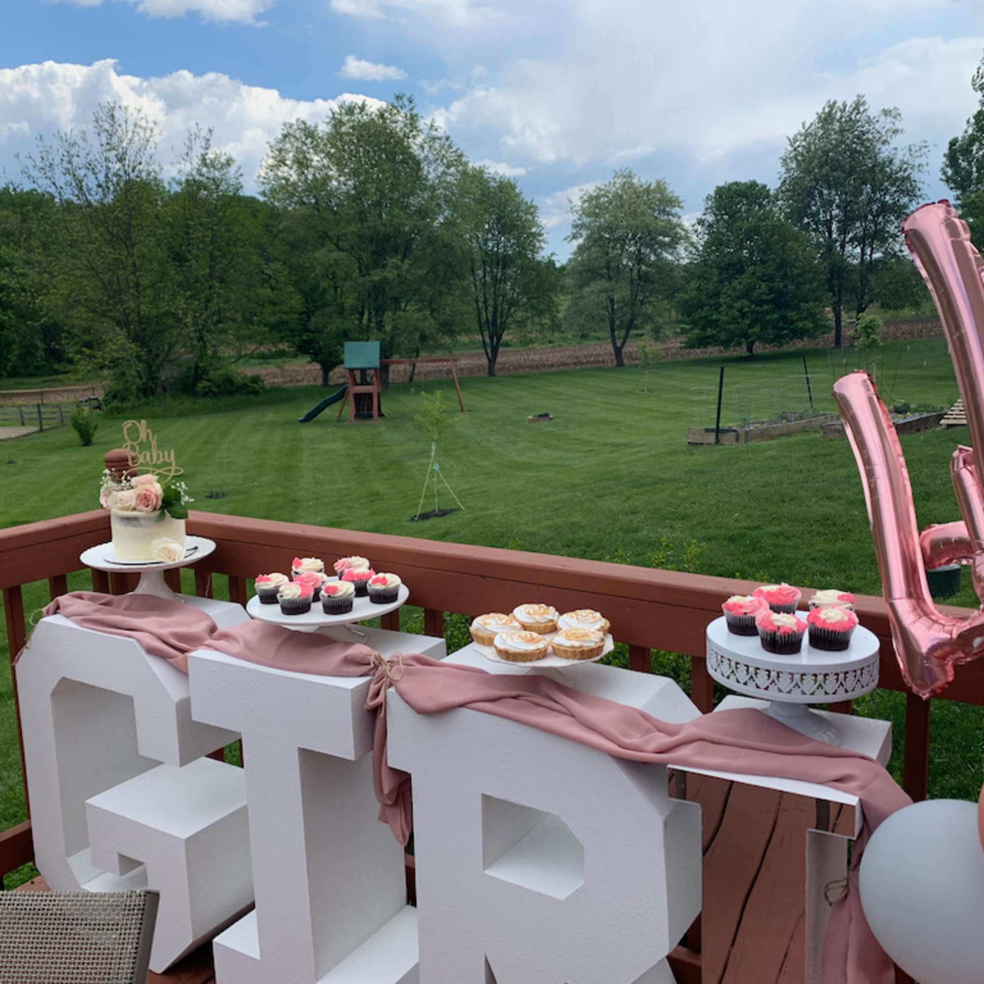 Baby shower dessert table with pink balloons and a small floral cake topper