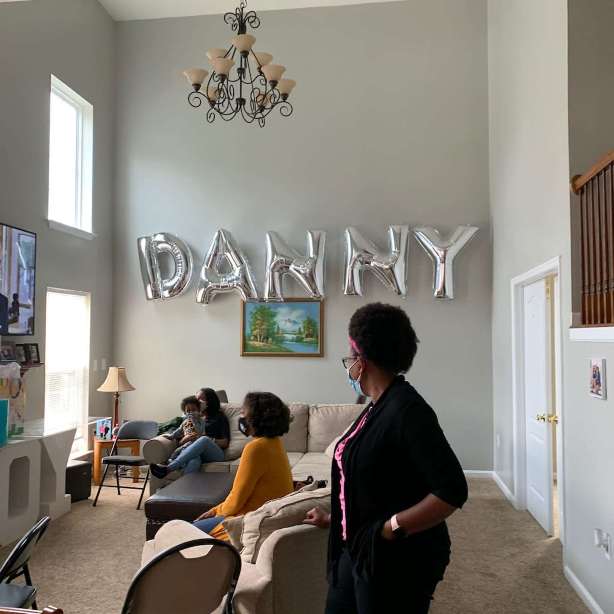 Living room with silver "DANNY" balloons and seated people