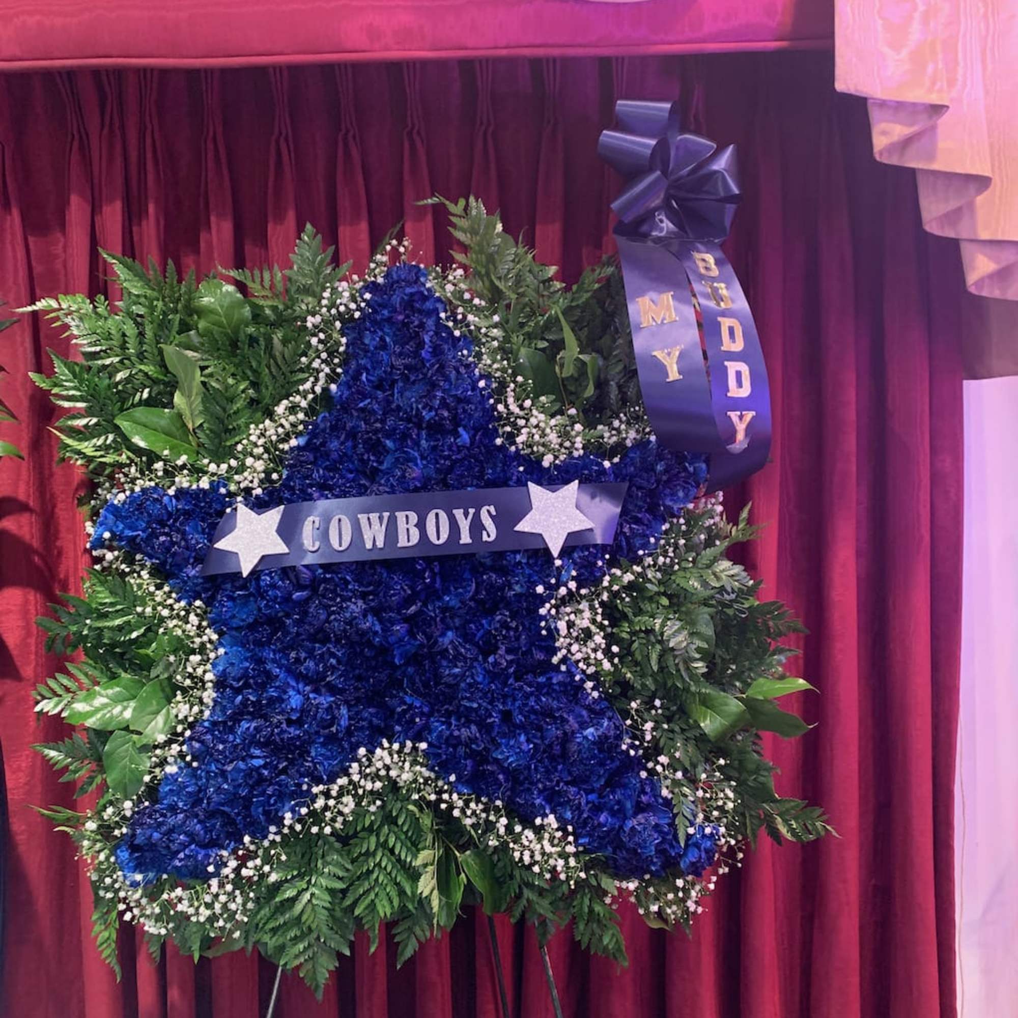 Blue floral star wreath with a Cowboys ribbon on a stand