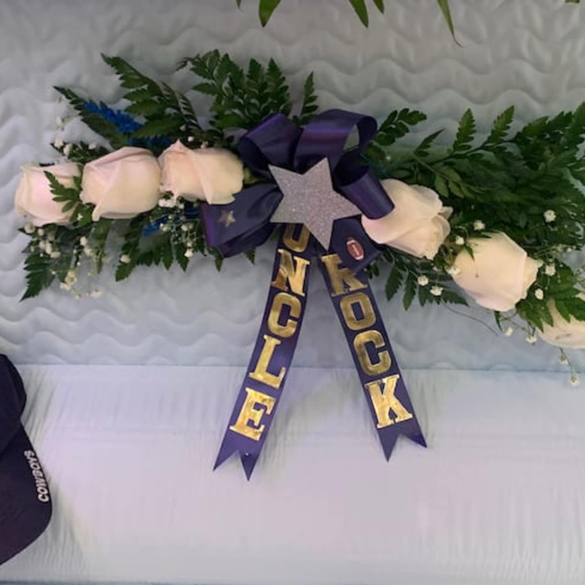 White roses and greenery with a purple ribbon and star decoration
