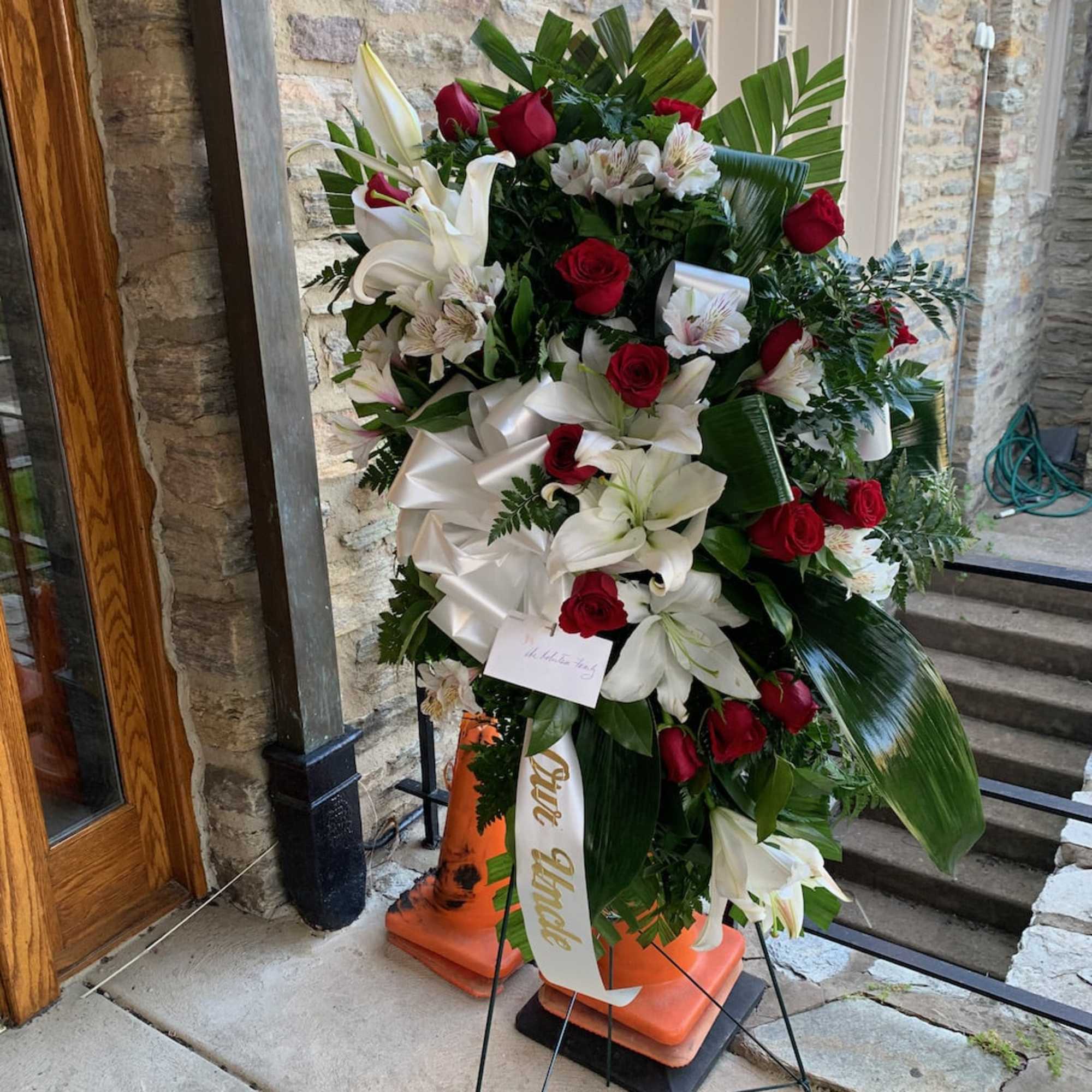 Standing floral spray with red roses and white lilies on an easel