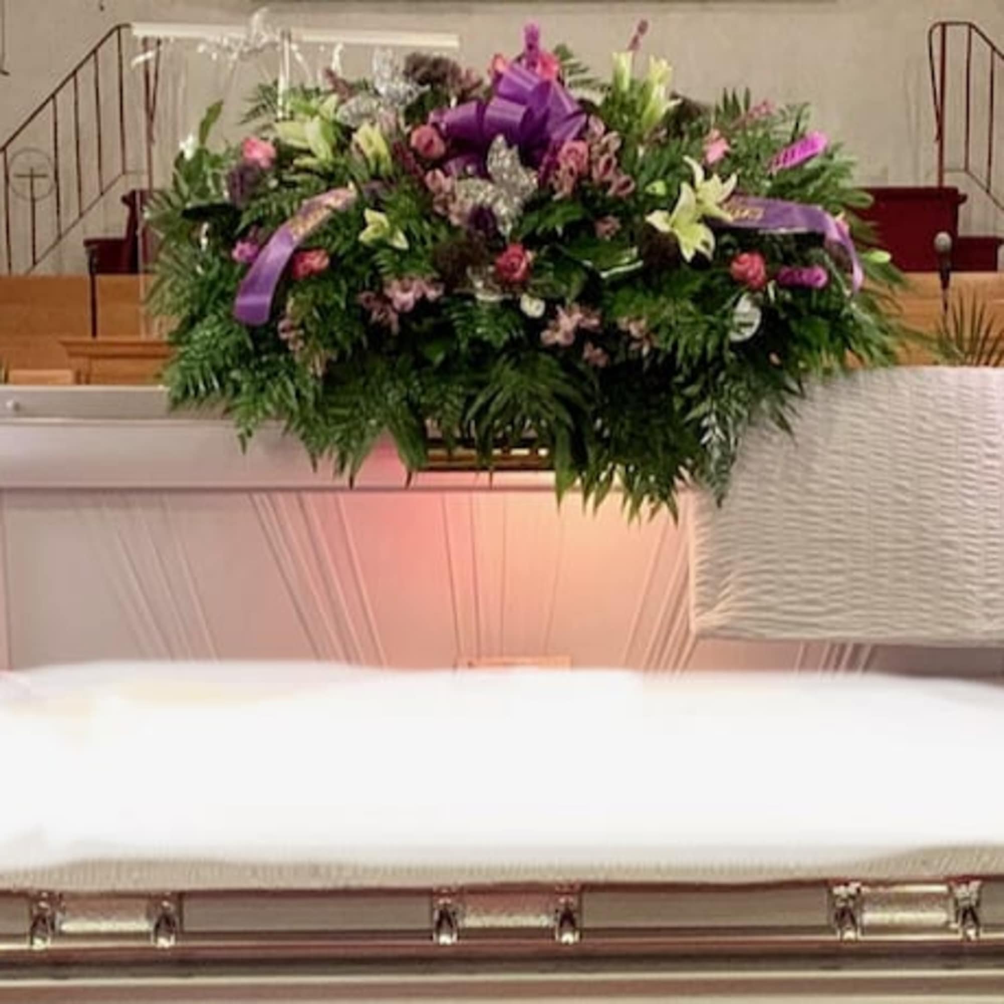 Casket spray with purple and white flowers in a church setting