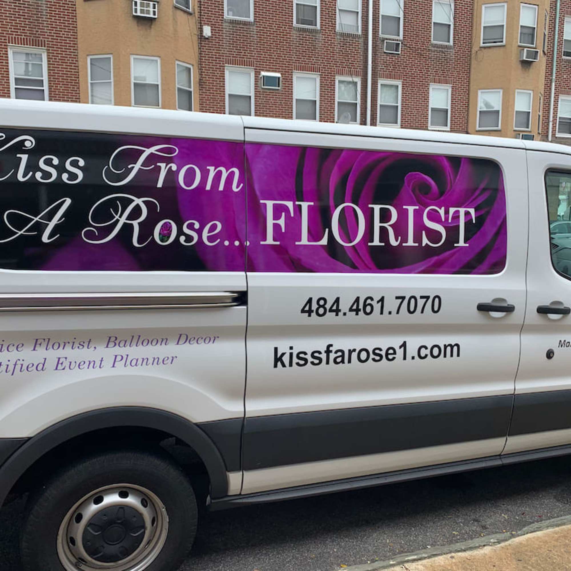 Branded florist van with a purple rose graphic and business text