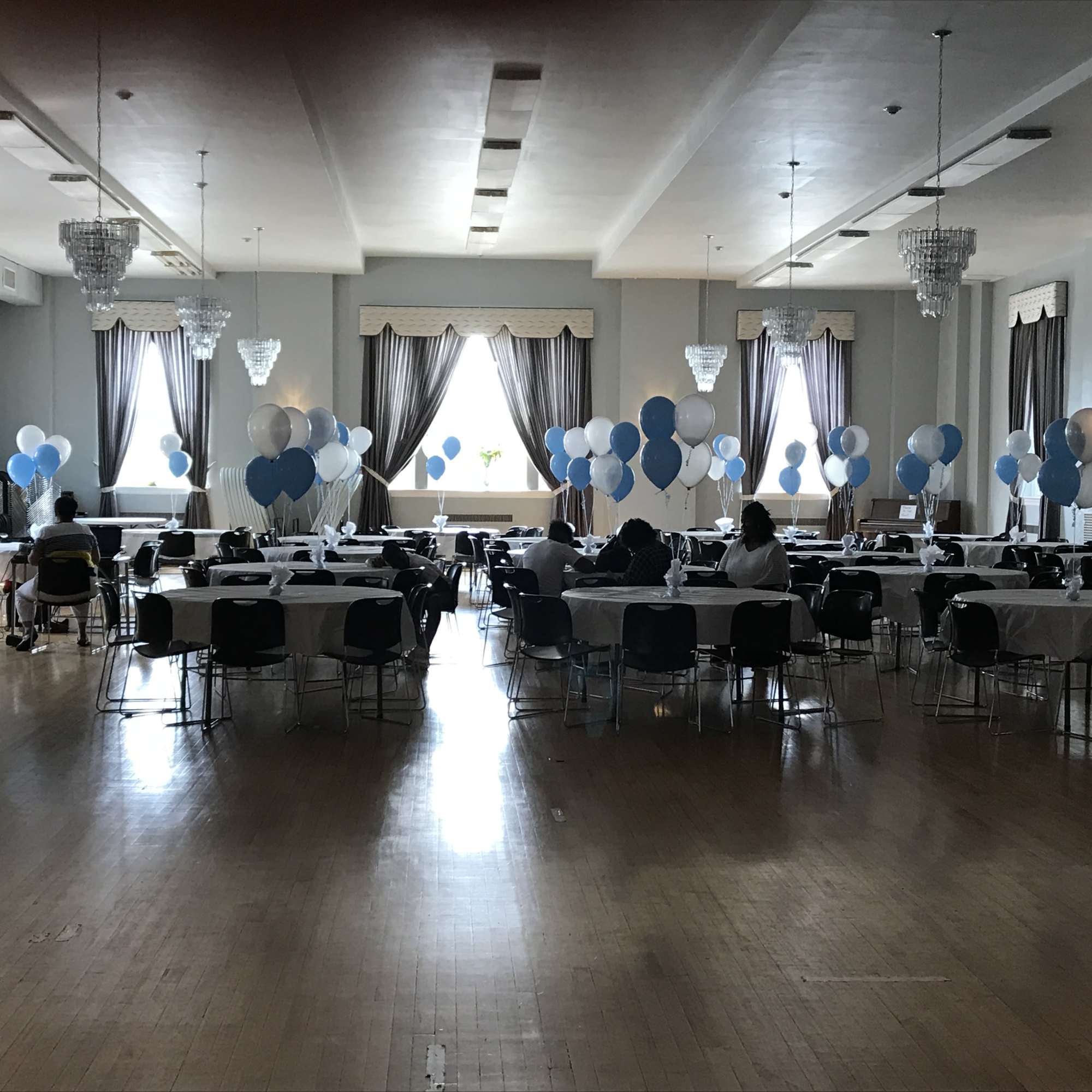 Balloon-decorated banquet hall with round tables and chairs