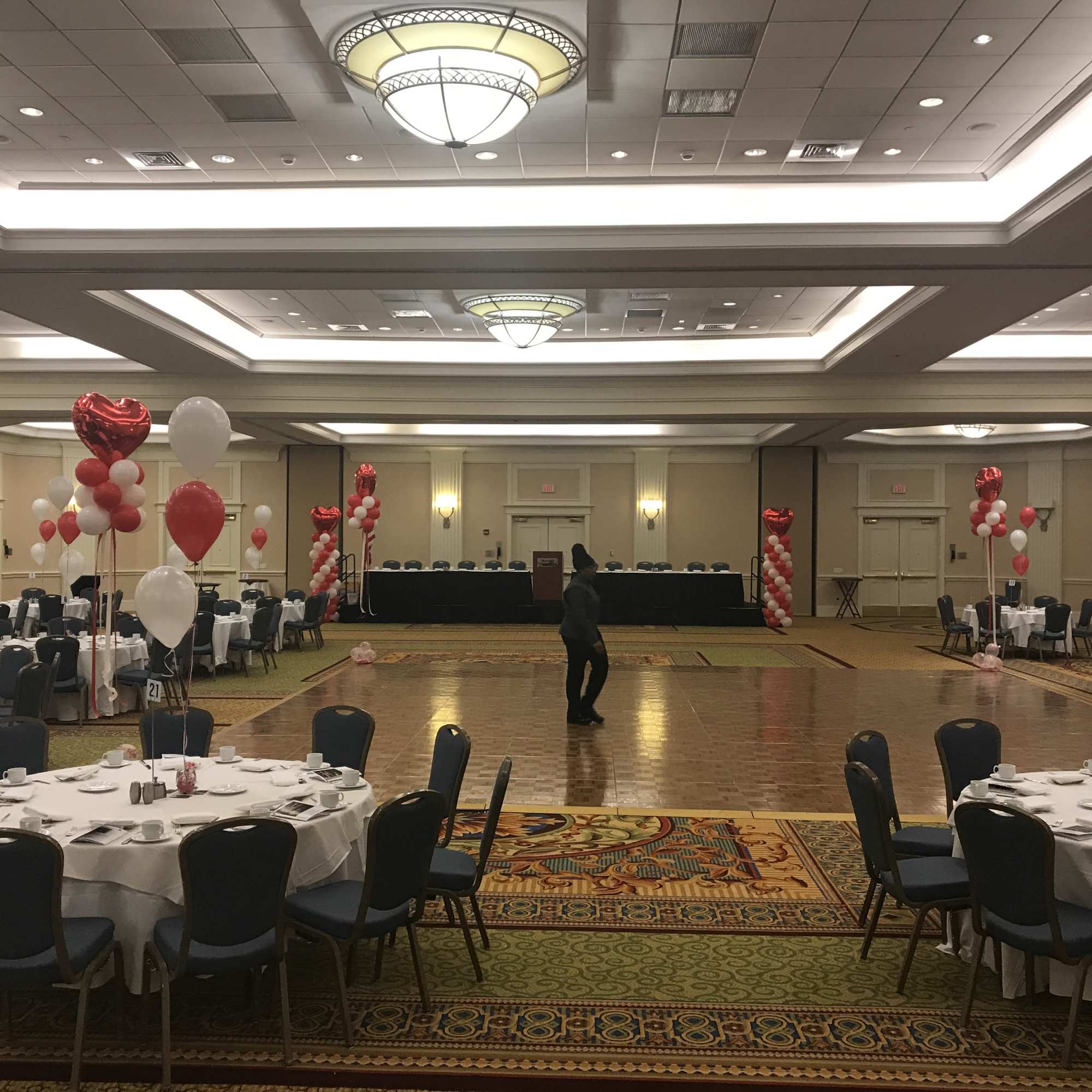 Balloon-decorated banquet hall with round tables and a dance floor