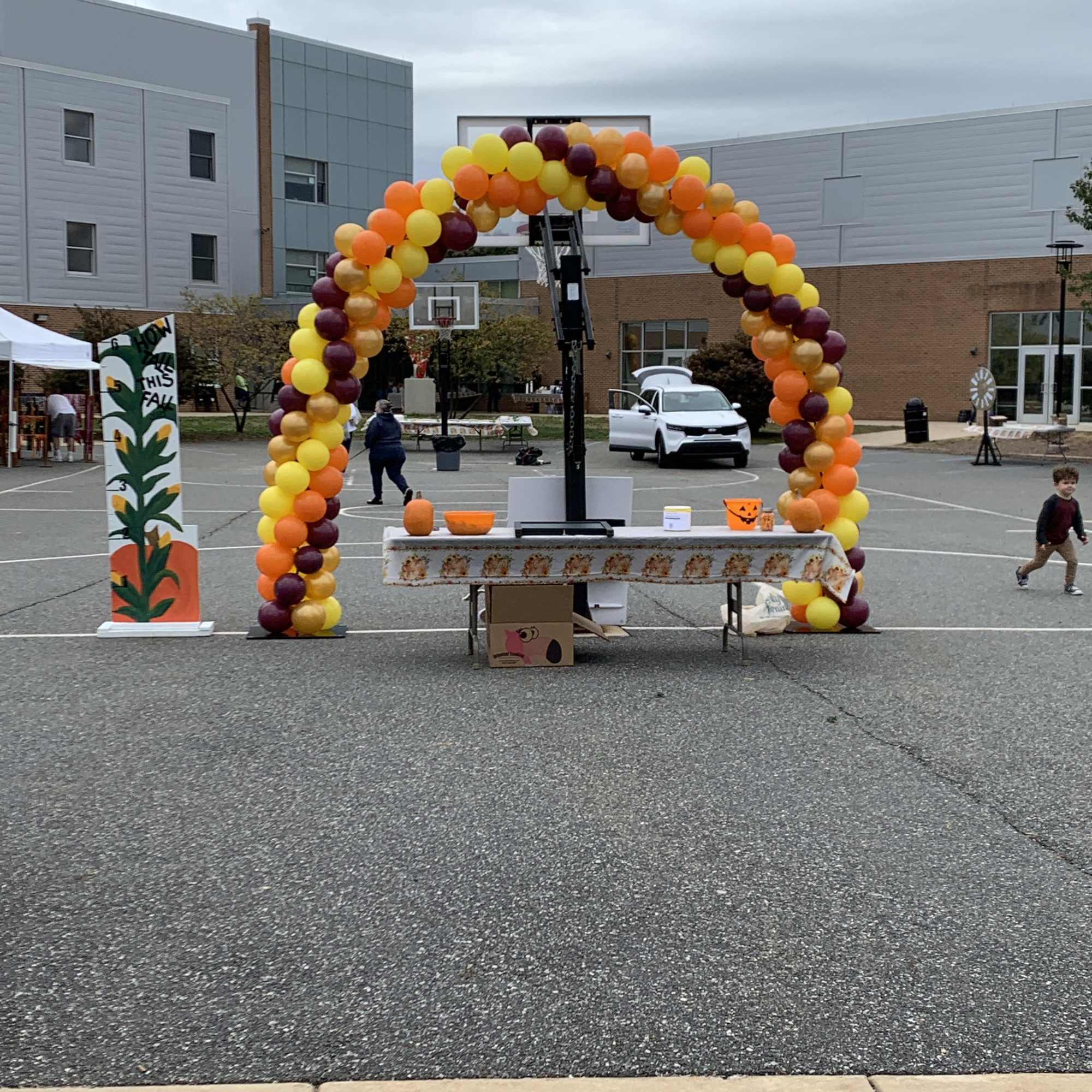 Balloon arch in yellow, orange, and burgundy at an outdoor event