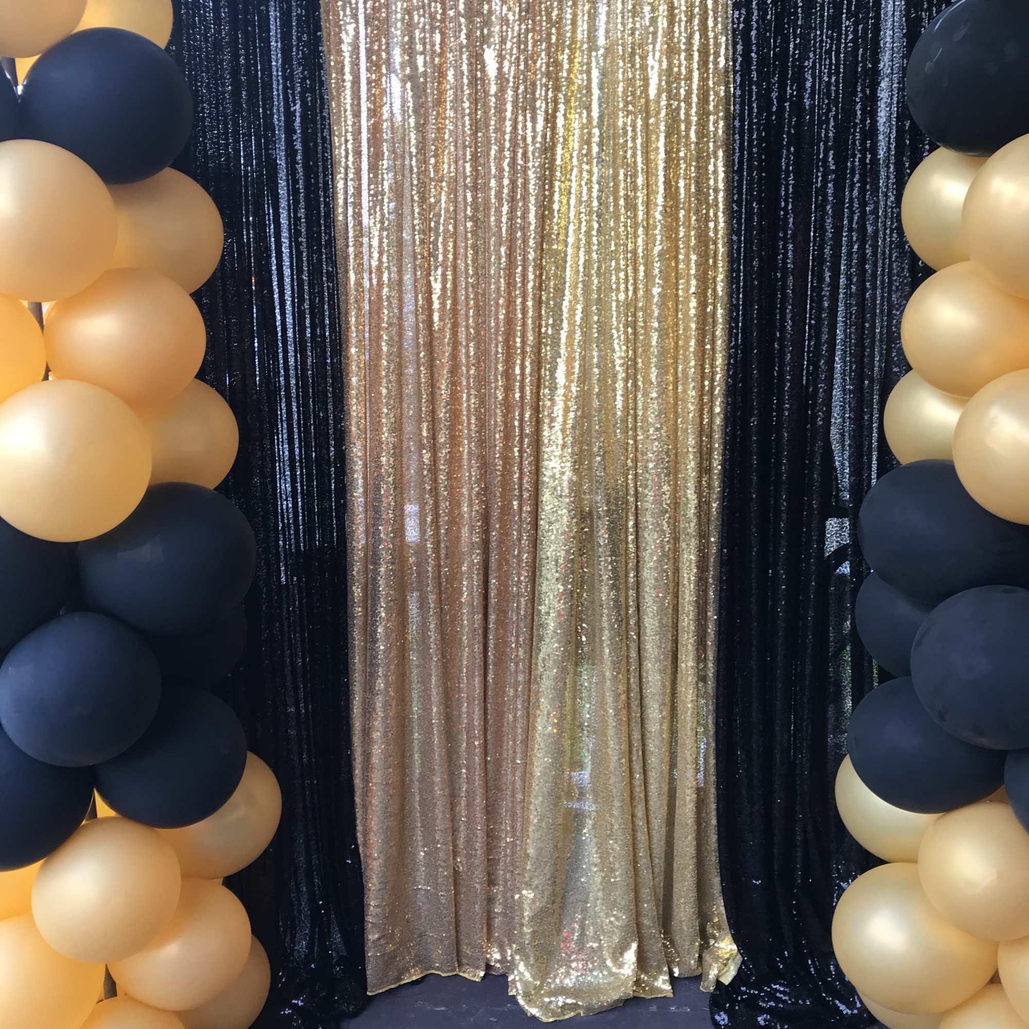 Gold and navy balloon columns frame a shimmering gold backdrop.
