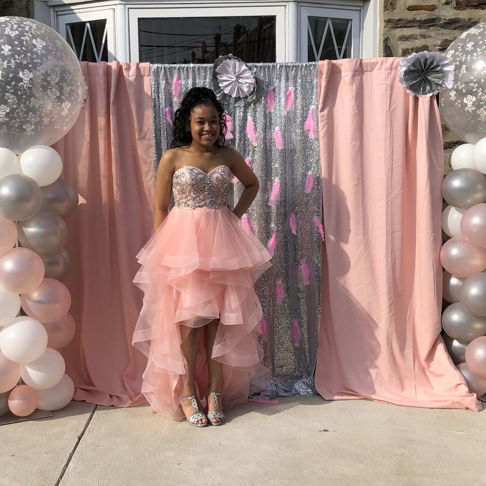 Girl in a pink dress posing in front of a balloon and draped backdrop