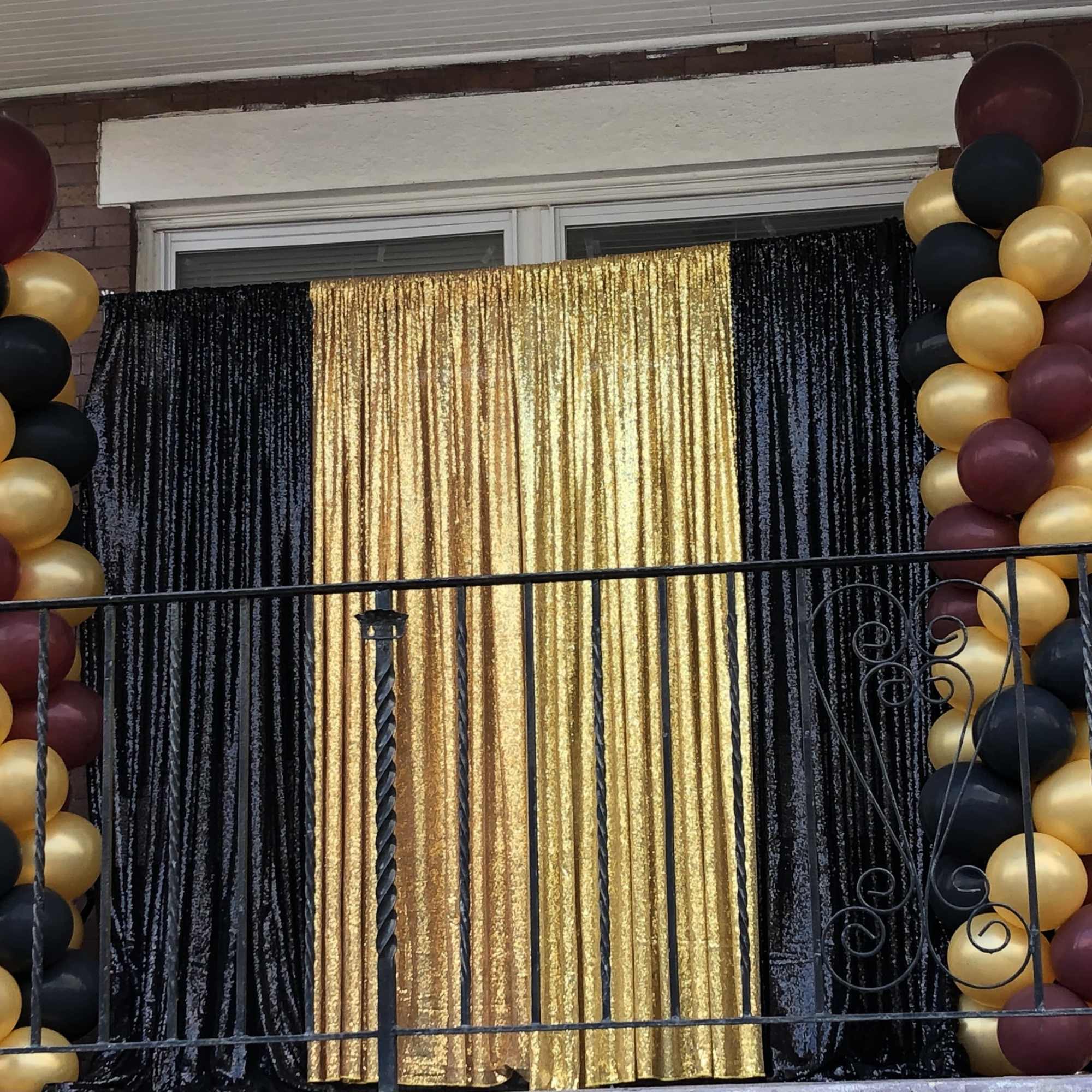 Black, gold, and burgundy balloon columns framing a gold and black backdrop