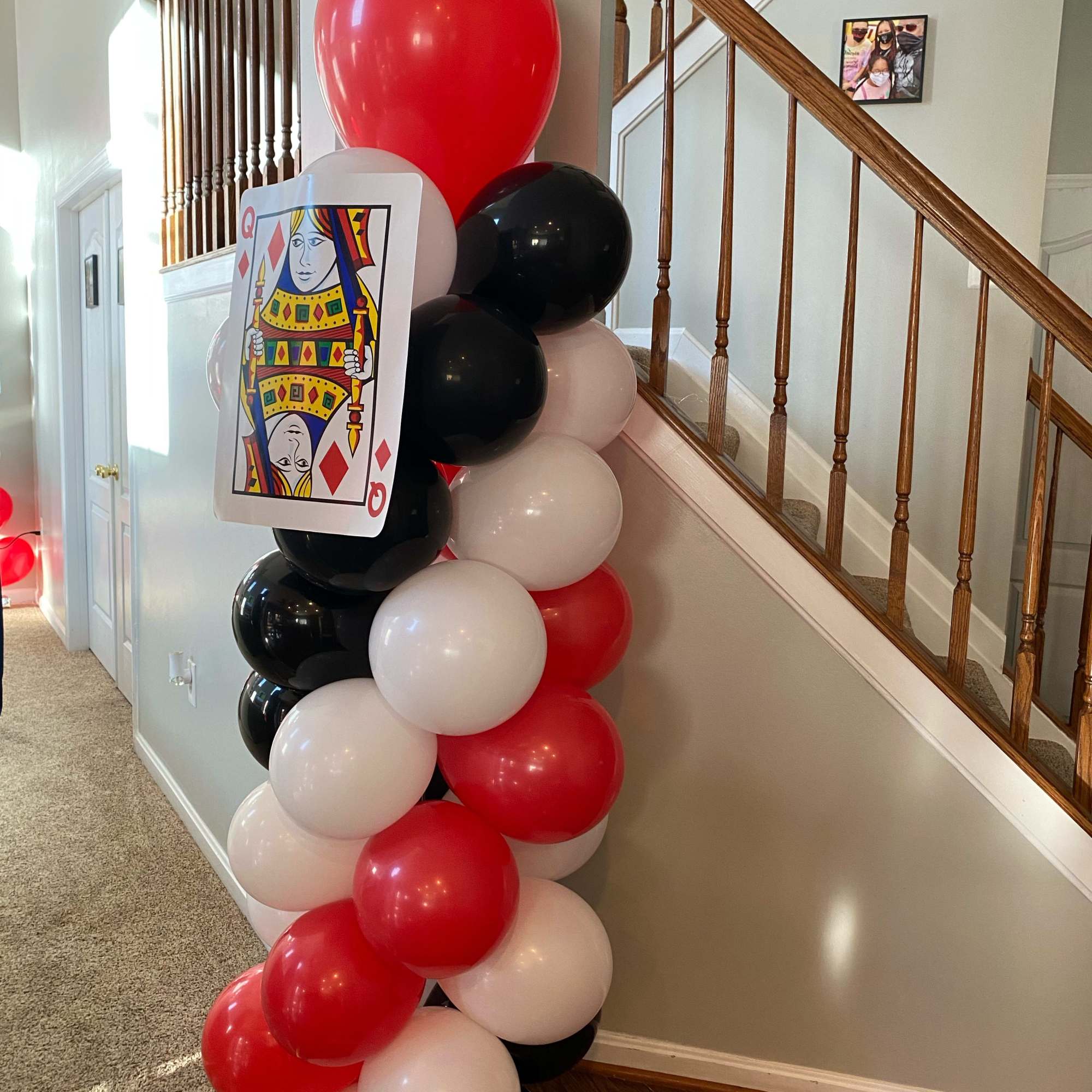 Red, black, and white balloon column with a playing card decoration