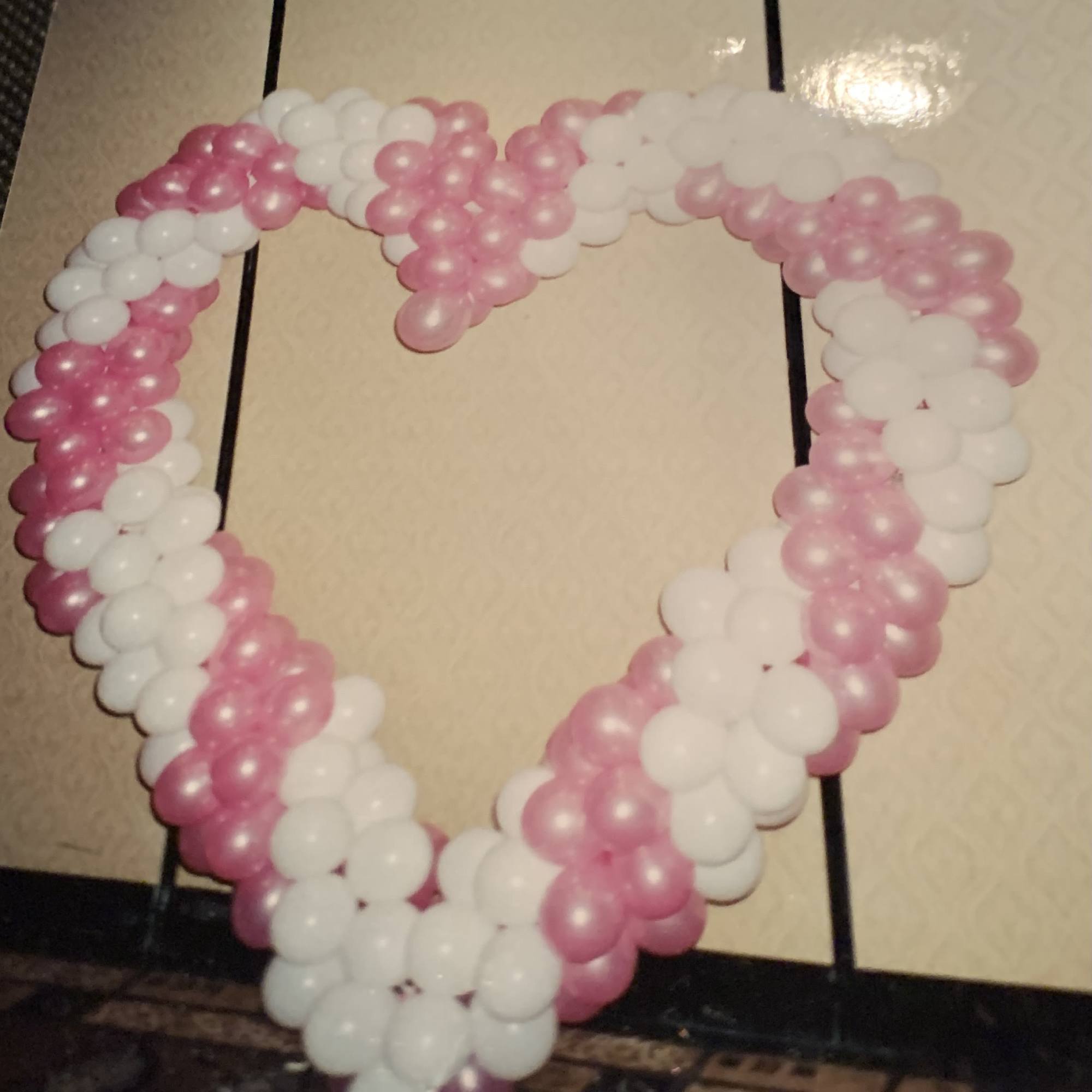 Pink and white balloon heart decoration on a wall