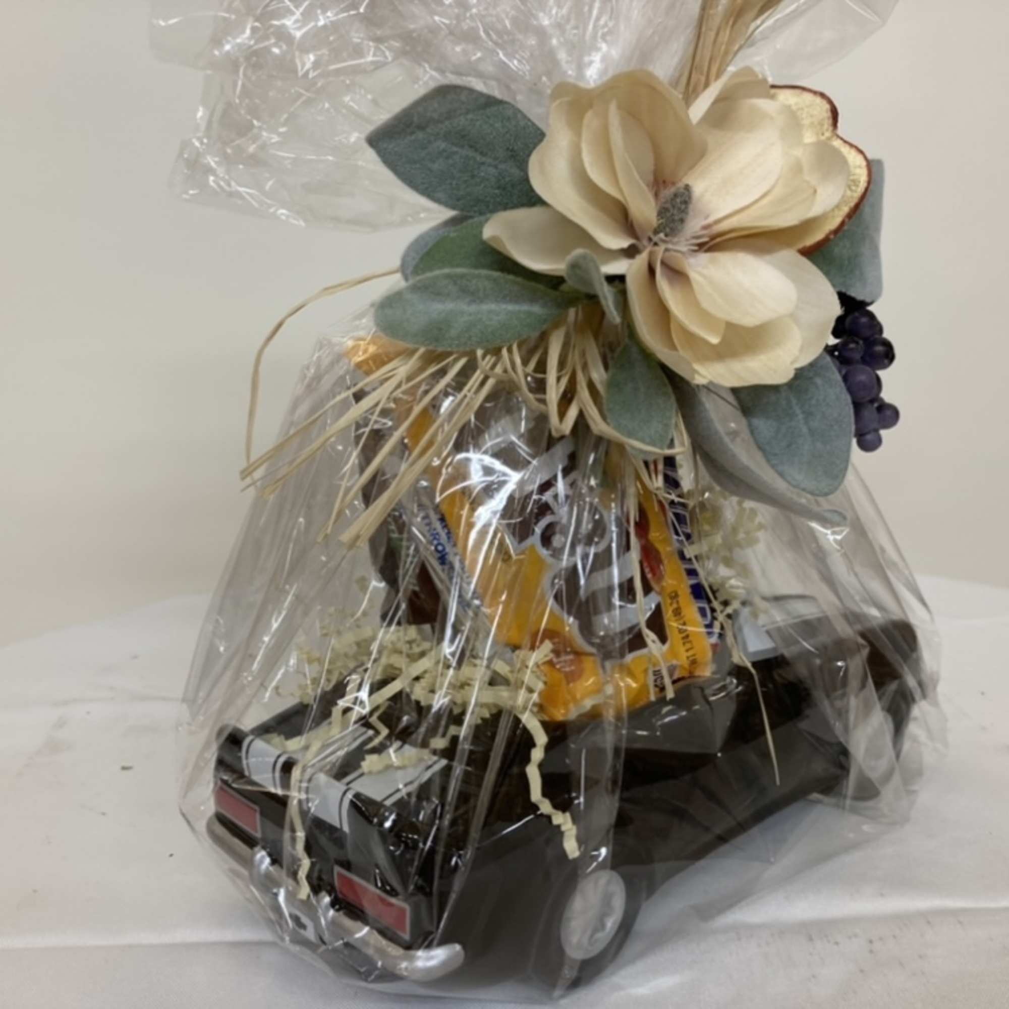 Gift basket wrapped in cellophane with a decorative flower topper