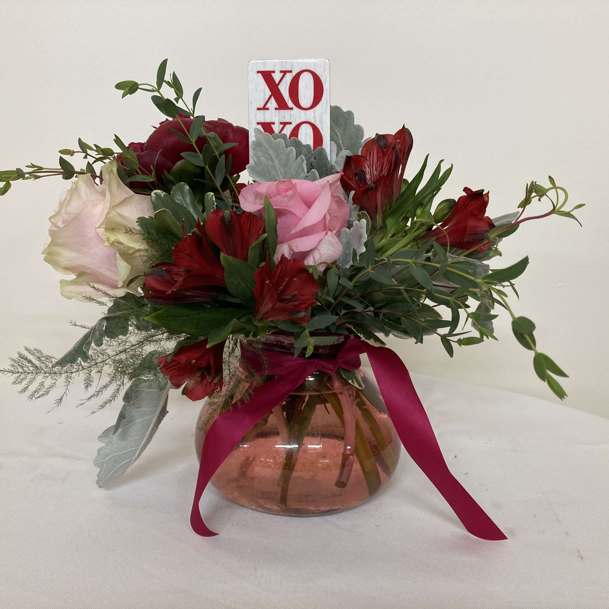 Bouquet of red and pink flowers in a glass vase with a ribbon