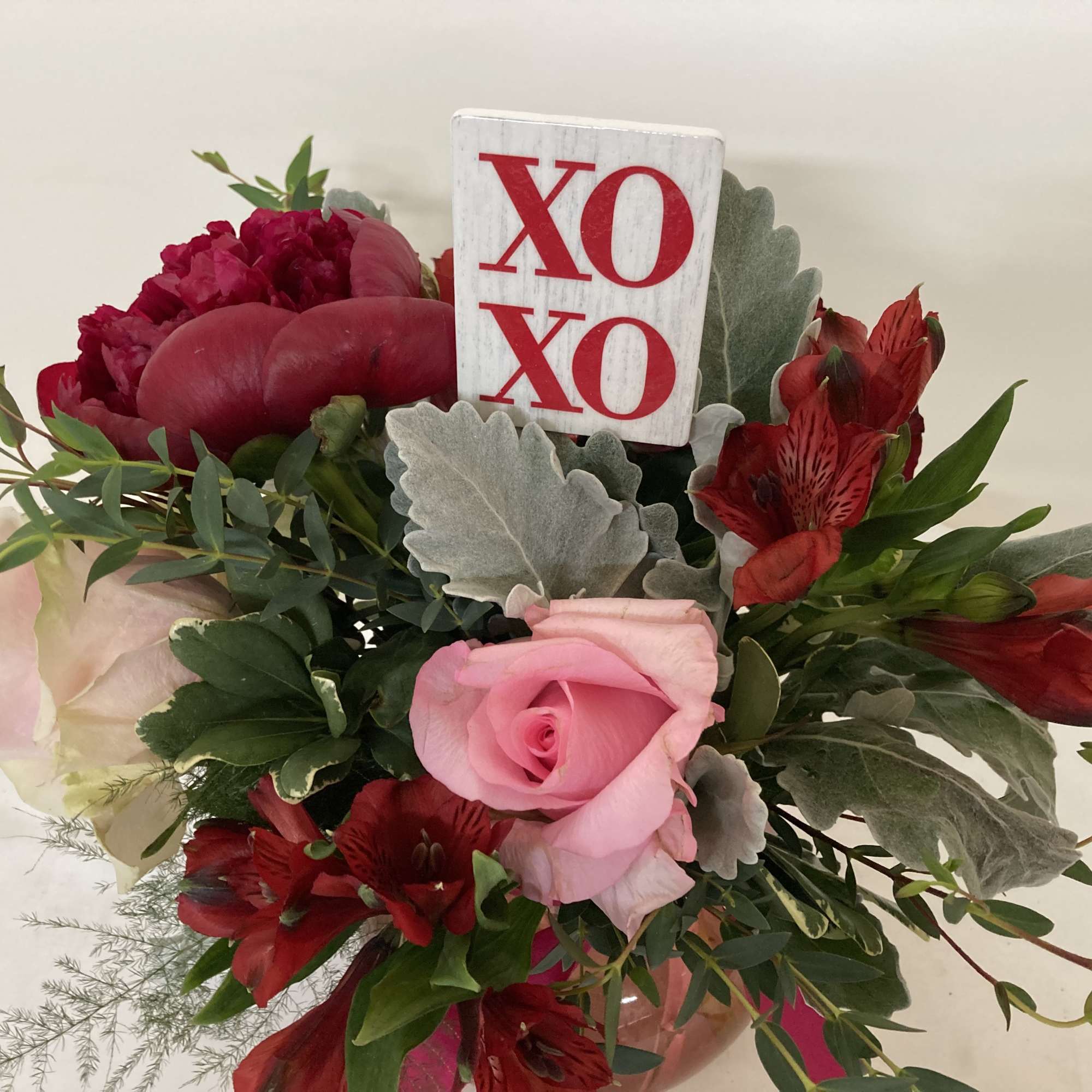 Bouquet of pink and red flowers with an XO sign