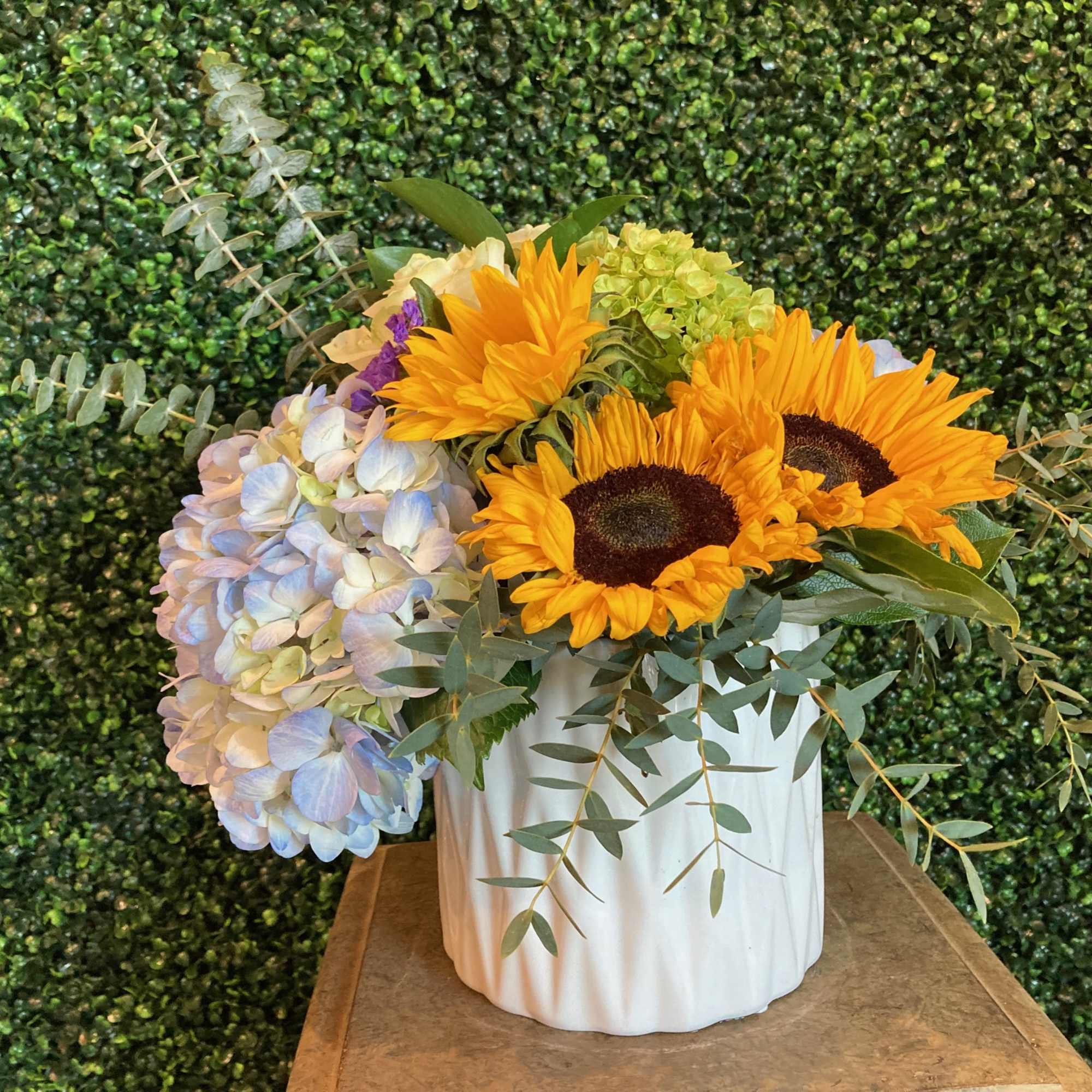 Sunflowers and pale hydrangeas arranged in a white vase