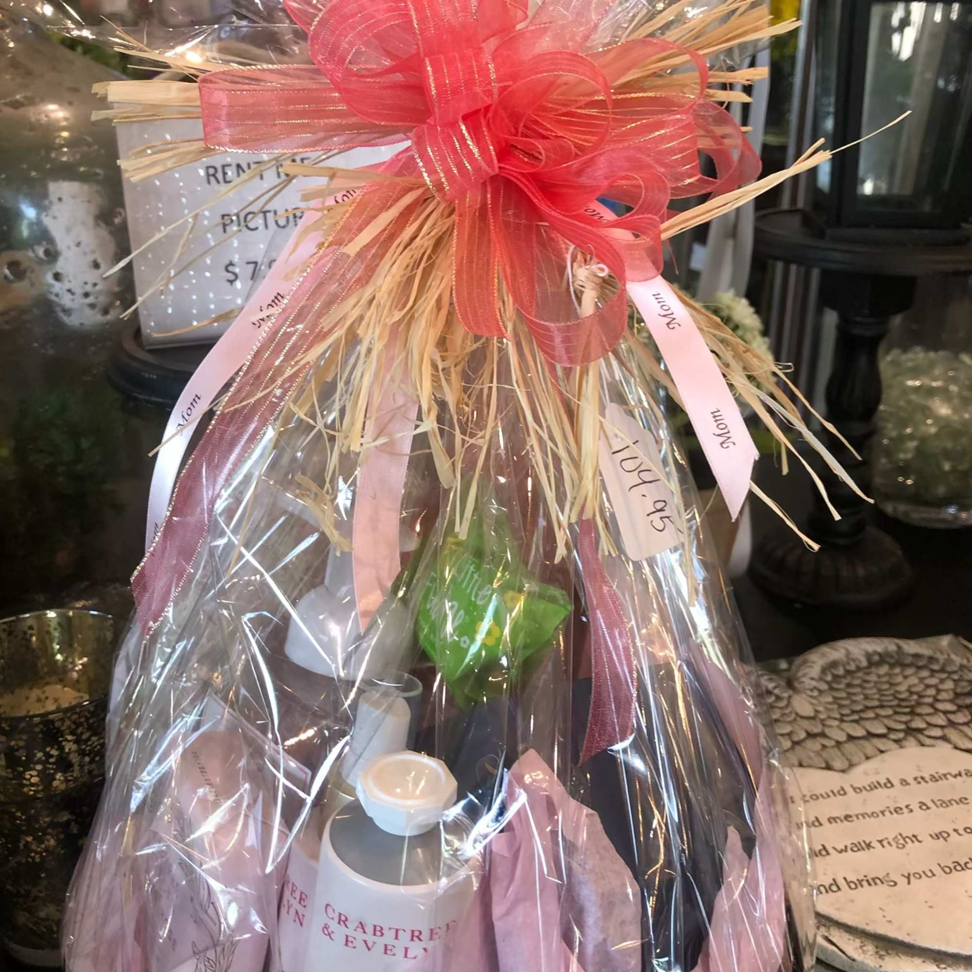 Gift basket wrapped in clear cellophane with a pink bow and assorted bath items